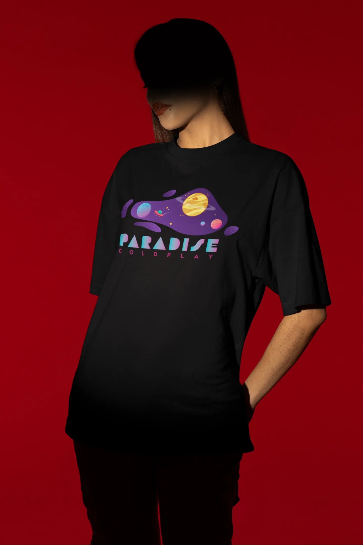 Second front view of a female model wearing an black oversized t-shirt with the "Paradise" album artwork by Coldplay.
