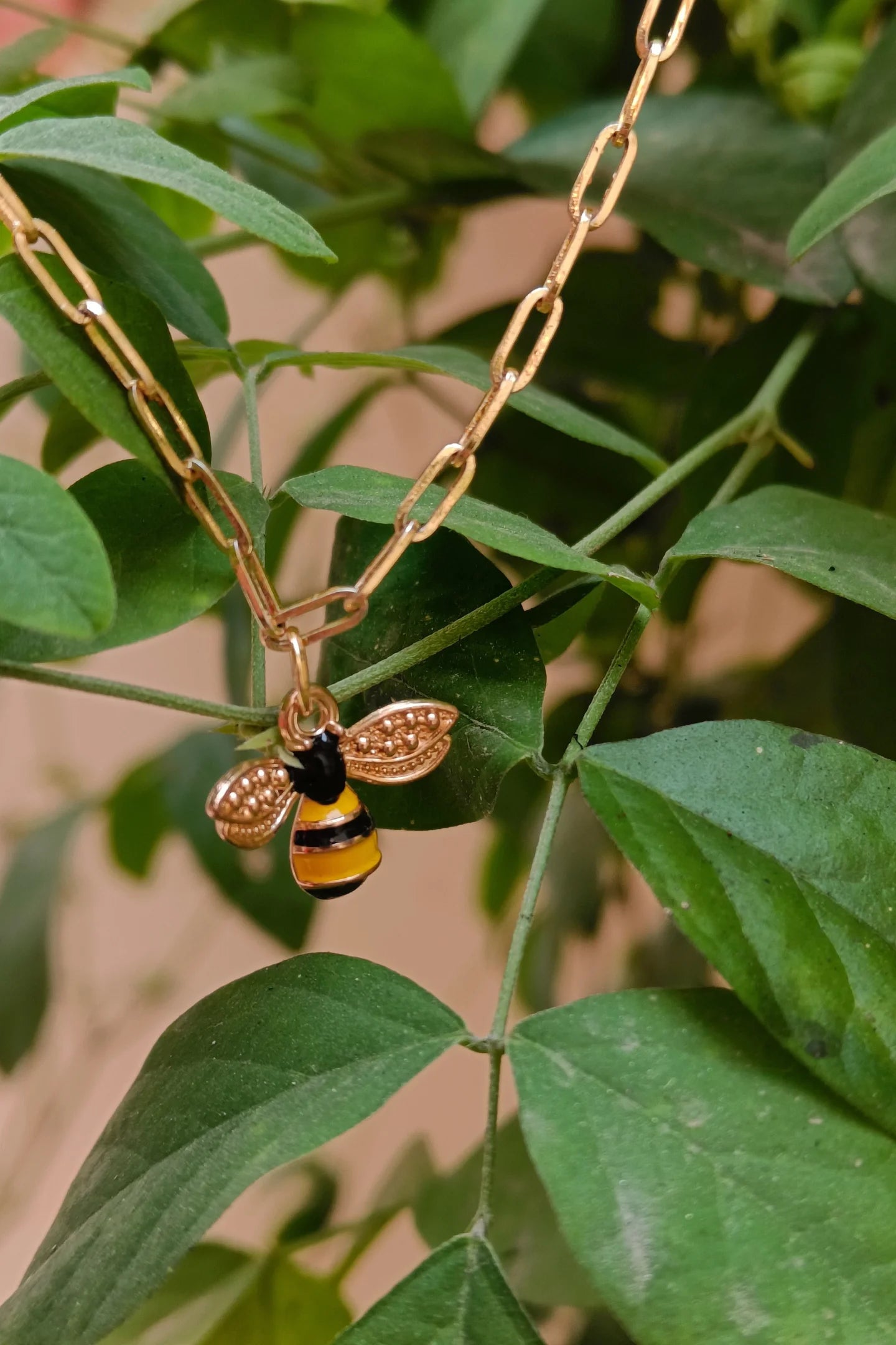 2nd view of a gold chain necklace with a small pendant shaped like a honey bee.