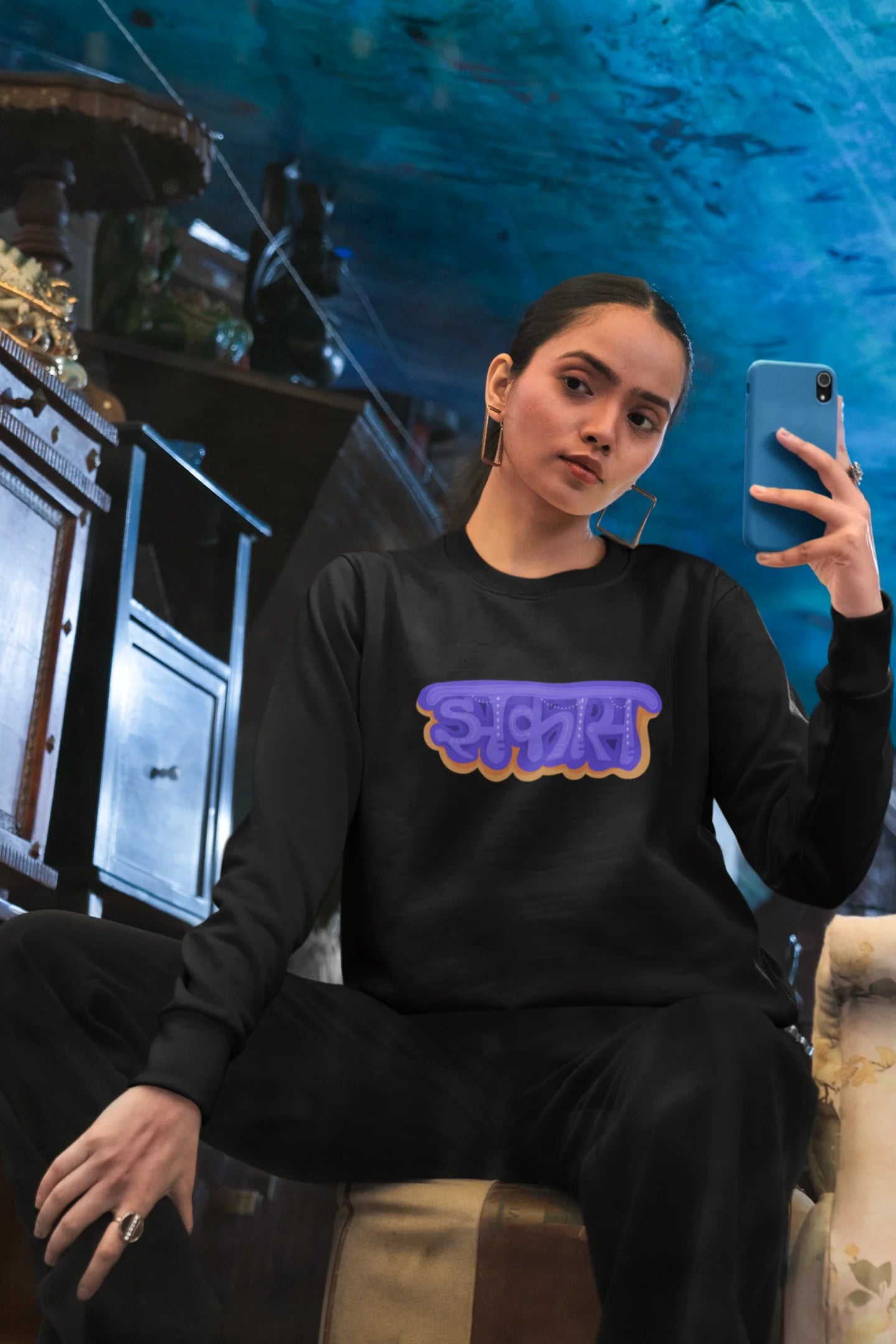 5th front view of a female model wearing an black sweatshirt featuring "Jhakas" in a stylish font.