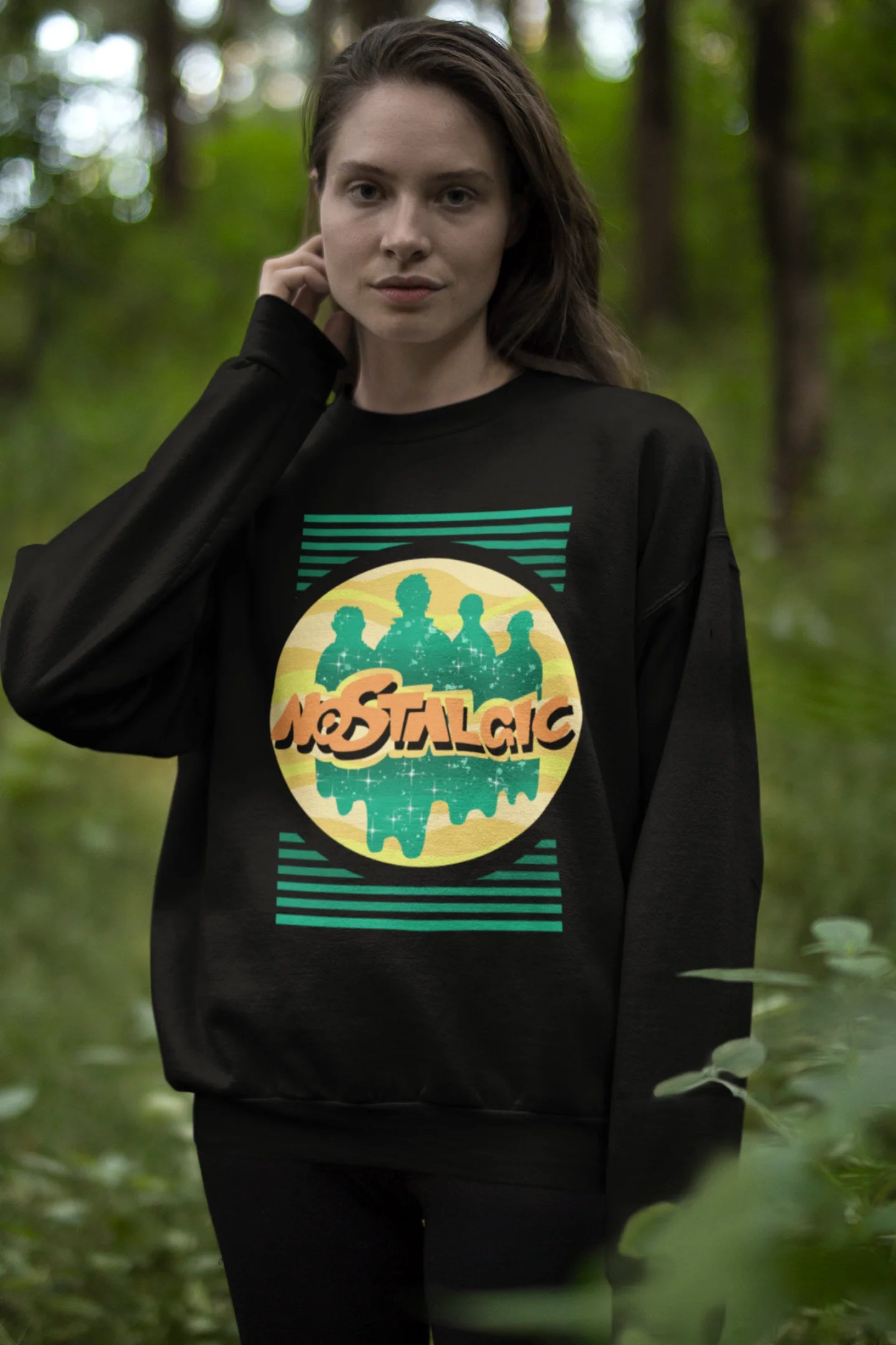 Fourth view of a female model wearing an oversized black sweatshirt with a shadow silhouette of the Coldplay band members and the word "Nostalgic" printed on it.
