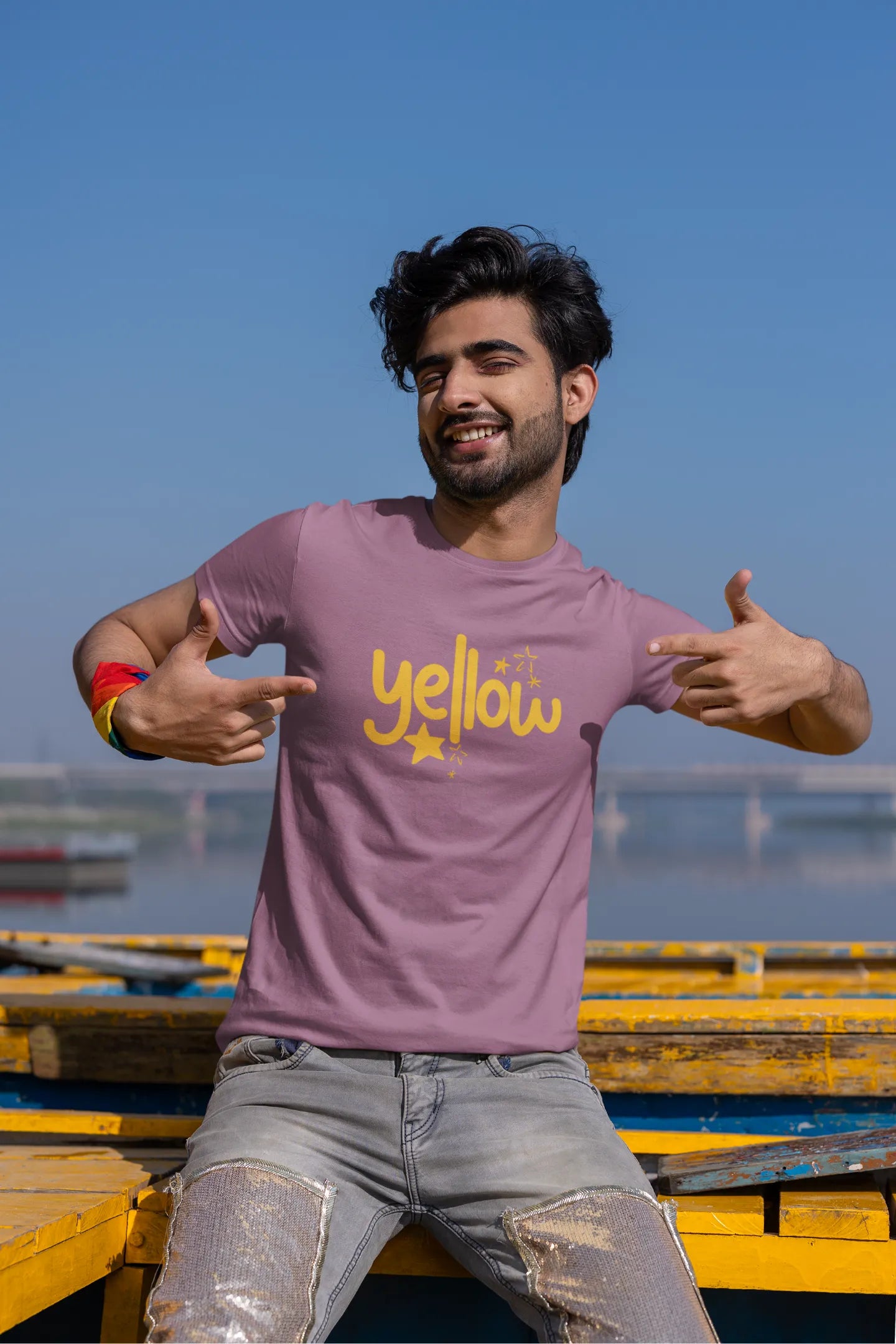 Fourth front view of a male model wearing a dirty purple oversized t-shirt with the "Yellow" album artwork by Coldplay.