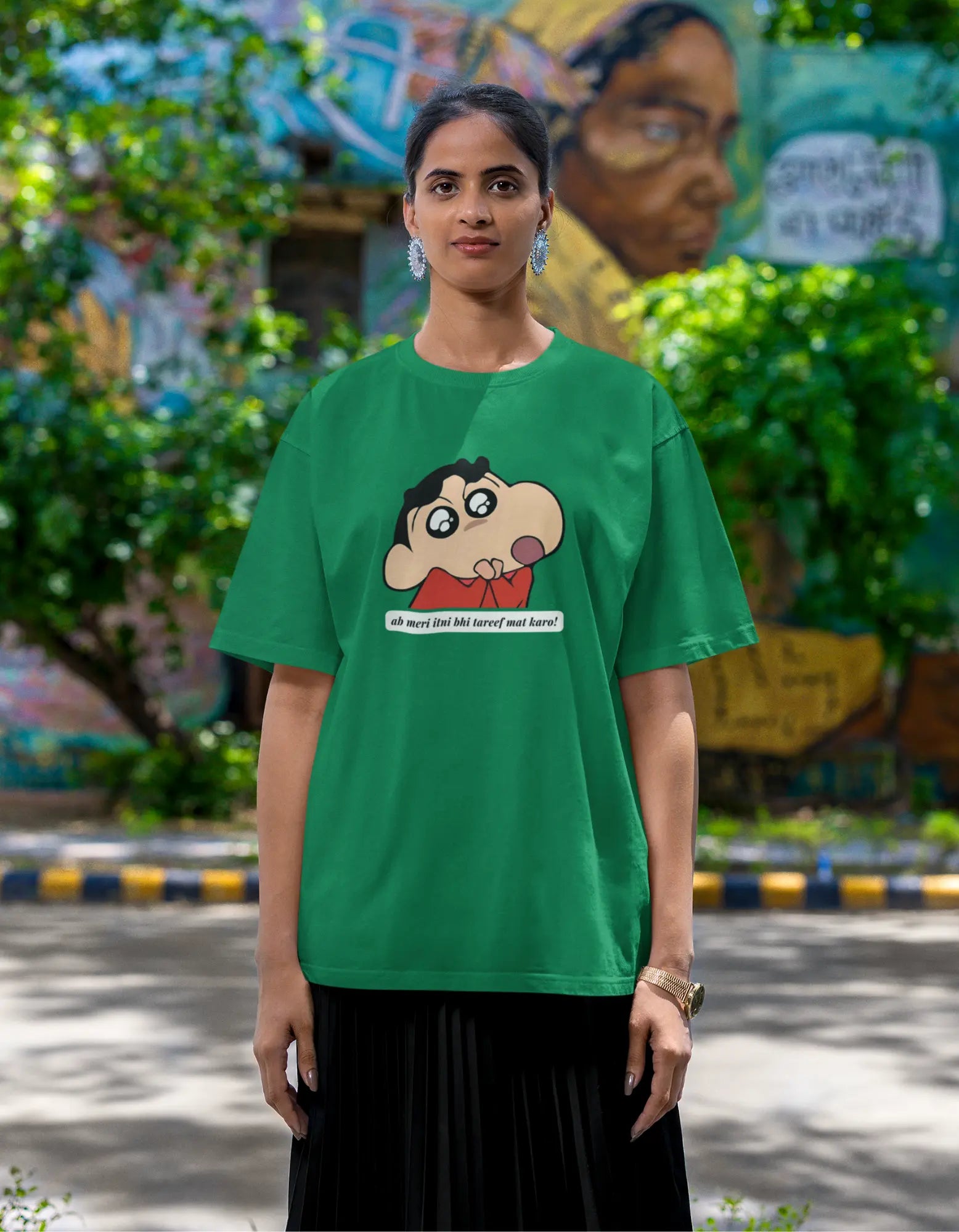 Second front view of female model wearing an oversized forest green tee featuring Shinchan with the text "Don't Praise Me So Much" in Hindi. A perfect blend of humor and nostalgia for Shinchan fans.