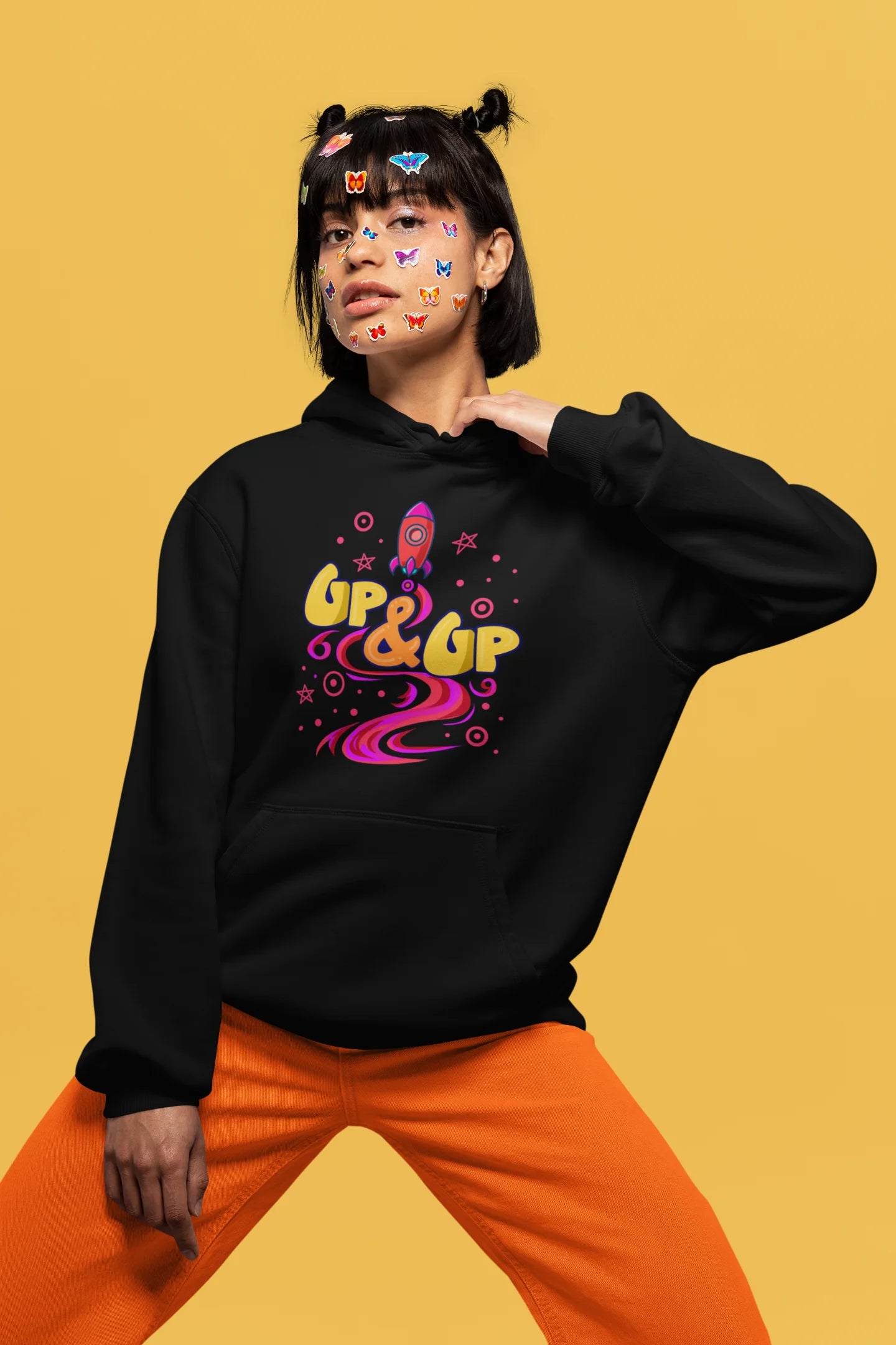 Fourth front view of a female model wearing an black hoodie with a rocket ship design and the text "Up & Up".