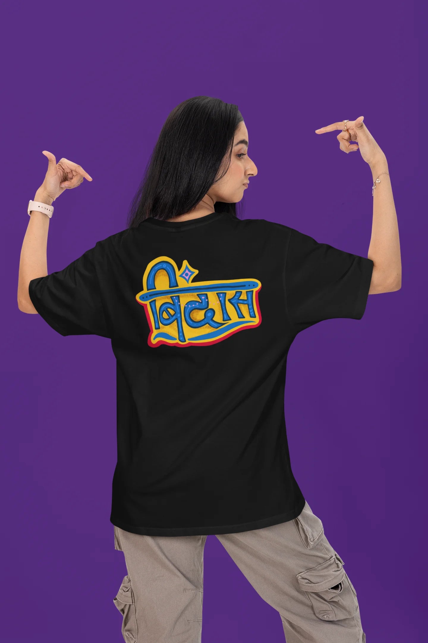 Back view of a female model wearing a black oversized t-shirt featuring "Bindass" in a stylish Hindi font.