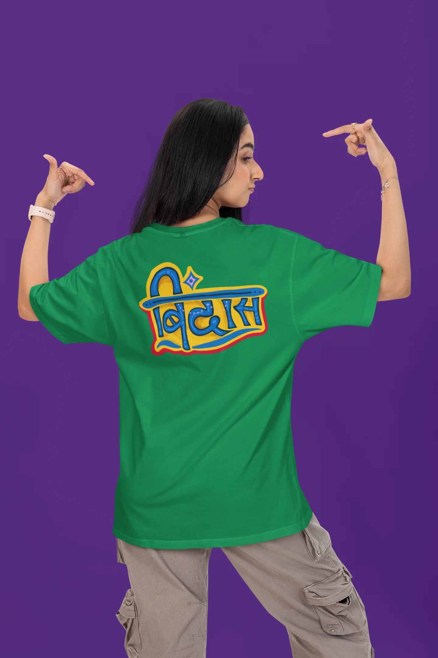 Back view of a female model wearing a forest green oversized t-shirt featuring "Bindass" in a stylish Hindi font.