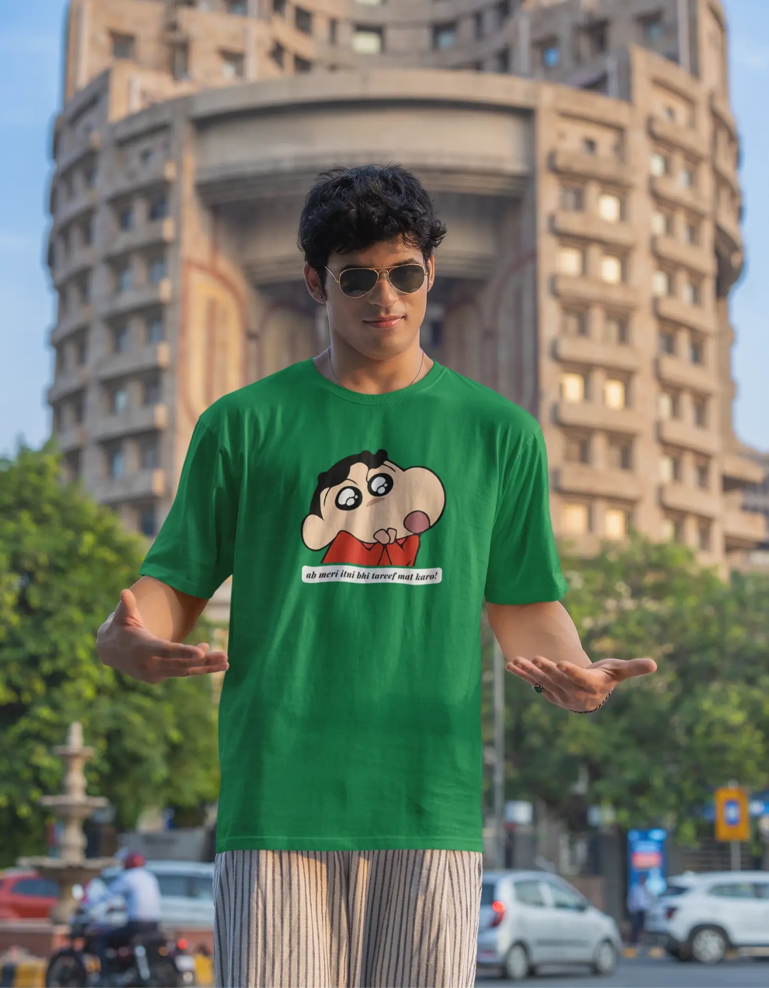 Third front view of male model wearing an oversized forest green tee featuring Shinchan with the text "Don't Praise Me So Much" in Hindi. A perfect blend of humor and nostalgia for Shinchan fans.