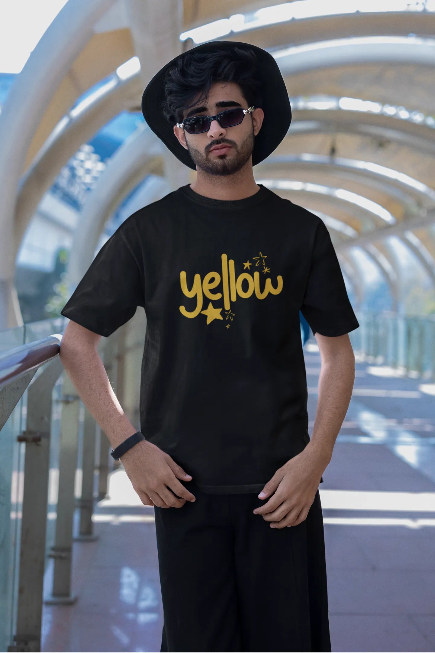 Second front view of a male model wearing a black oversized t-shirt with the "Yellow" album artwork by Coldplay.