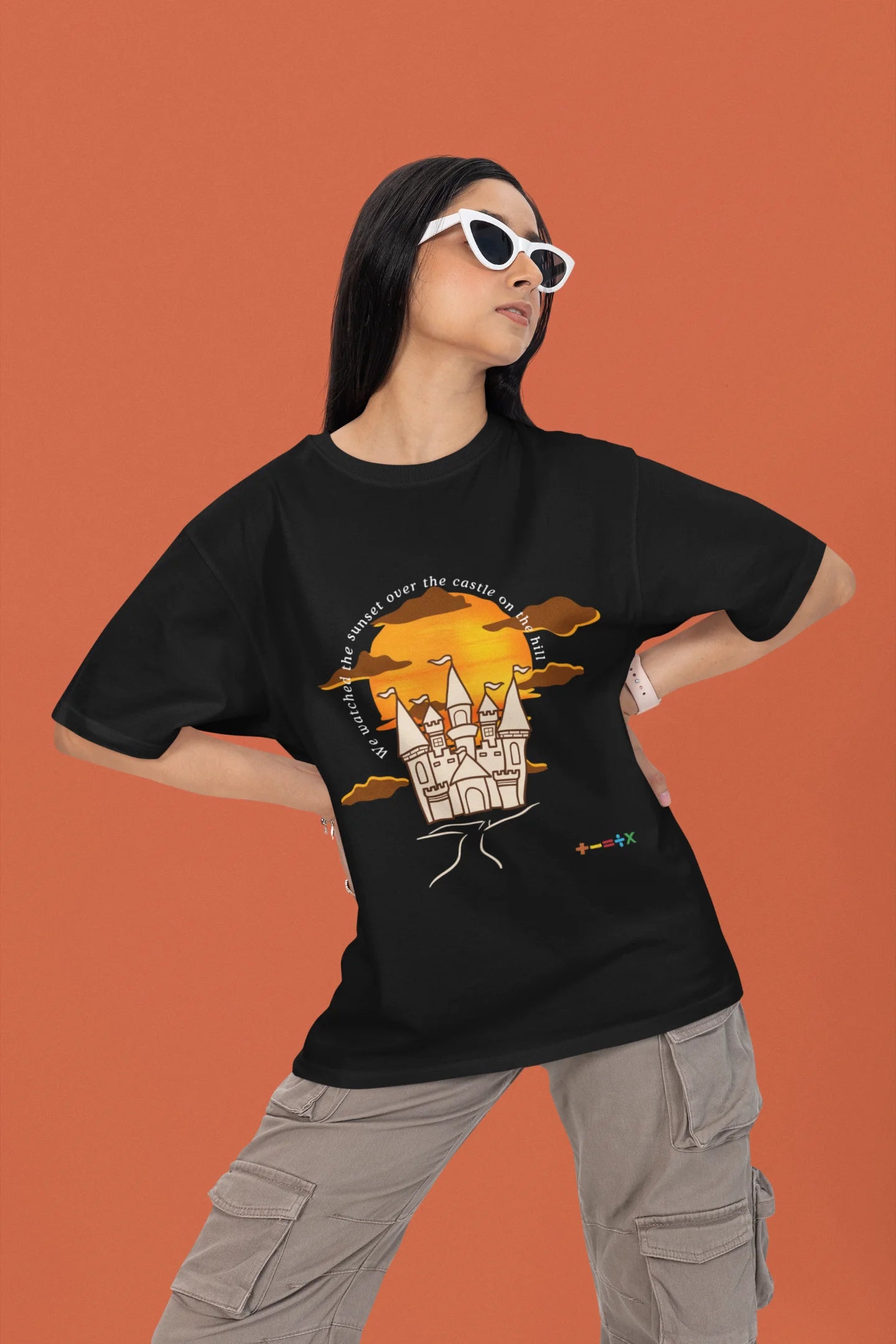2nd front view of a female model wearing a black oversized t-shirt featuring a nostalgic sunset and castle design, related to Ed Sheeran's "Castle on the Hill."