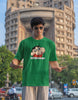 Third front view of male model wearing an oversized forest green tee featuring Shinchan with the text 