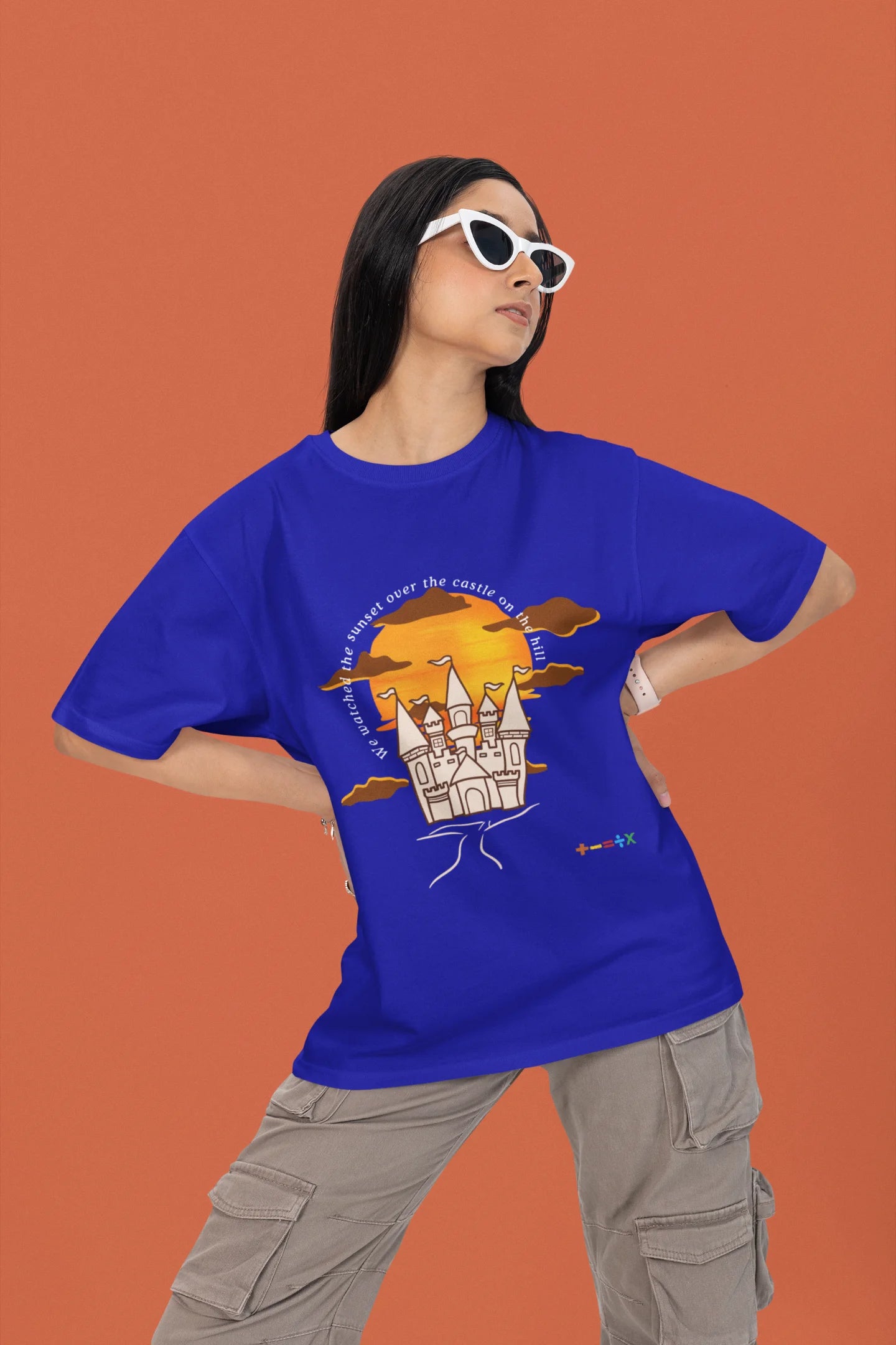 2nd front view of a female model wearing a royal blue oversized t-shirt featuring a nostalgic sunset and castle design, related to Ed Sheeran's "Castle on the Hill."