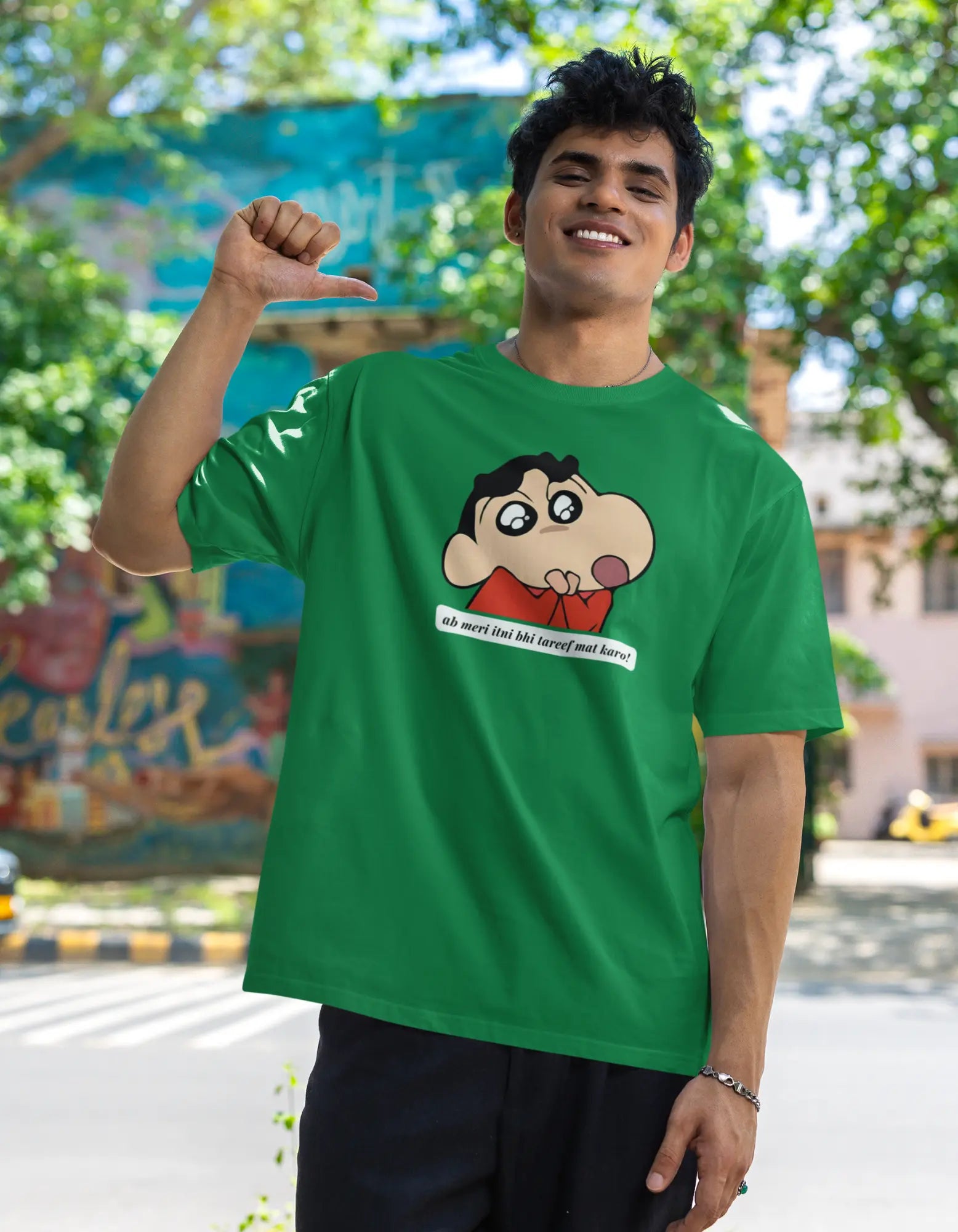 Front view of male model wearing an oversized forest green tee featuring Shinchan with the text "Don't Praise Me So Much" in Hindi. A perfect blend of humor and nostalgia for Shinchan fans.