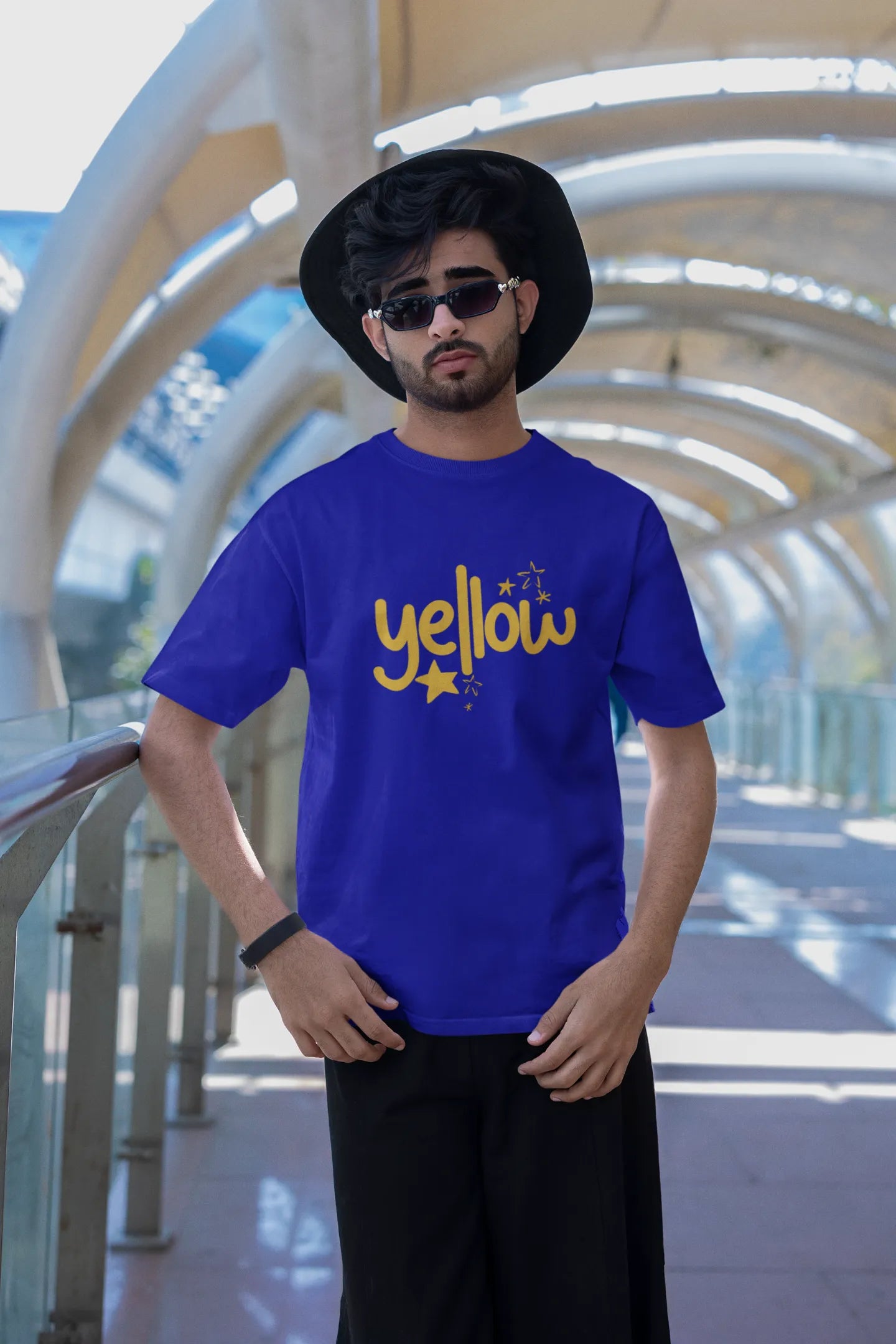 First front view of a male model wearing a royal blue oversized t-shirt with the "Yellow" album artwork by Coldplay.