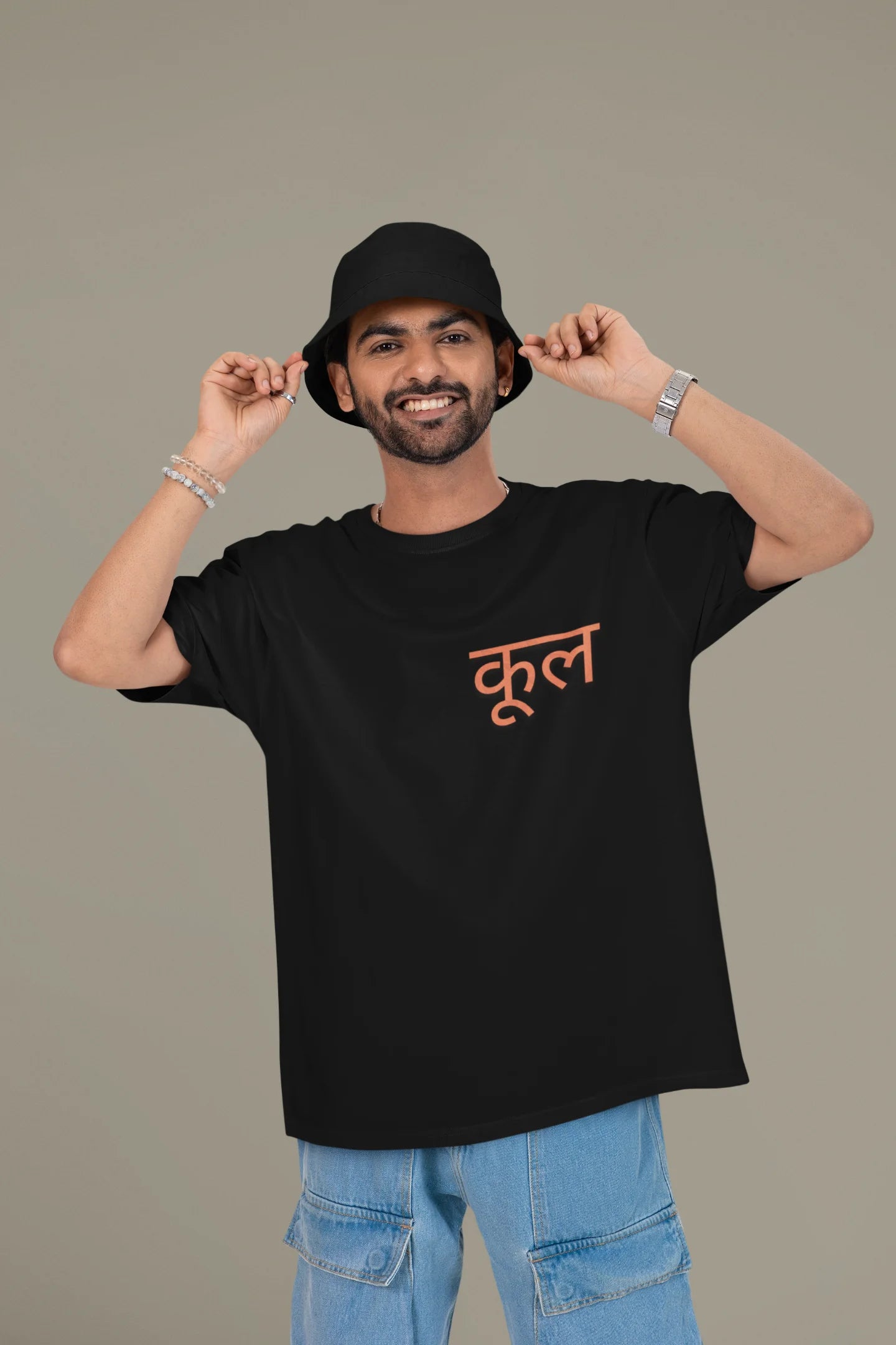 First front view of a male model wearing a black oversized t-shirt featuring the Hindi word for "cool" with a unique, playful design.