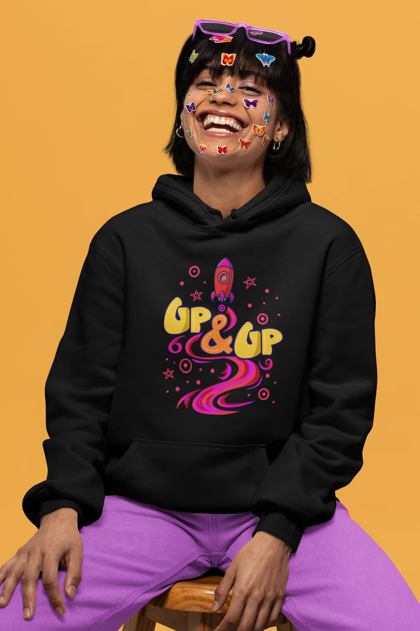 First front view of a female model wearing an black hoodie with a rocket ship design and the text "Up & Up".
