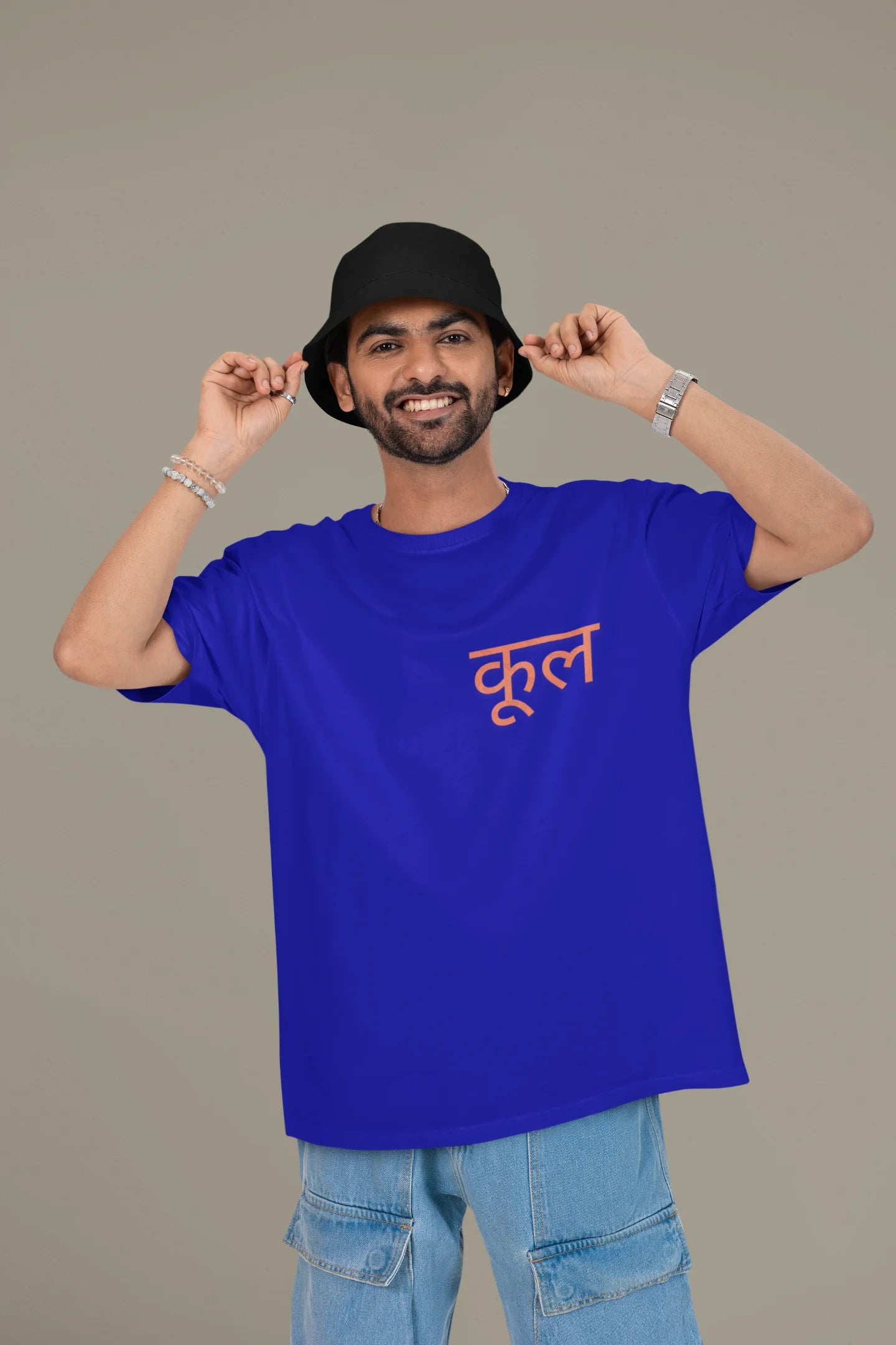 First front view of a male model wearing a royal blue oversized t-shirt featuring the Hindi word for "cool" with a unique, playful design.