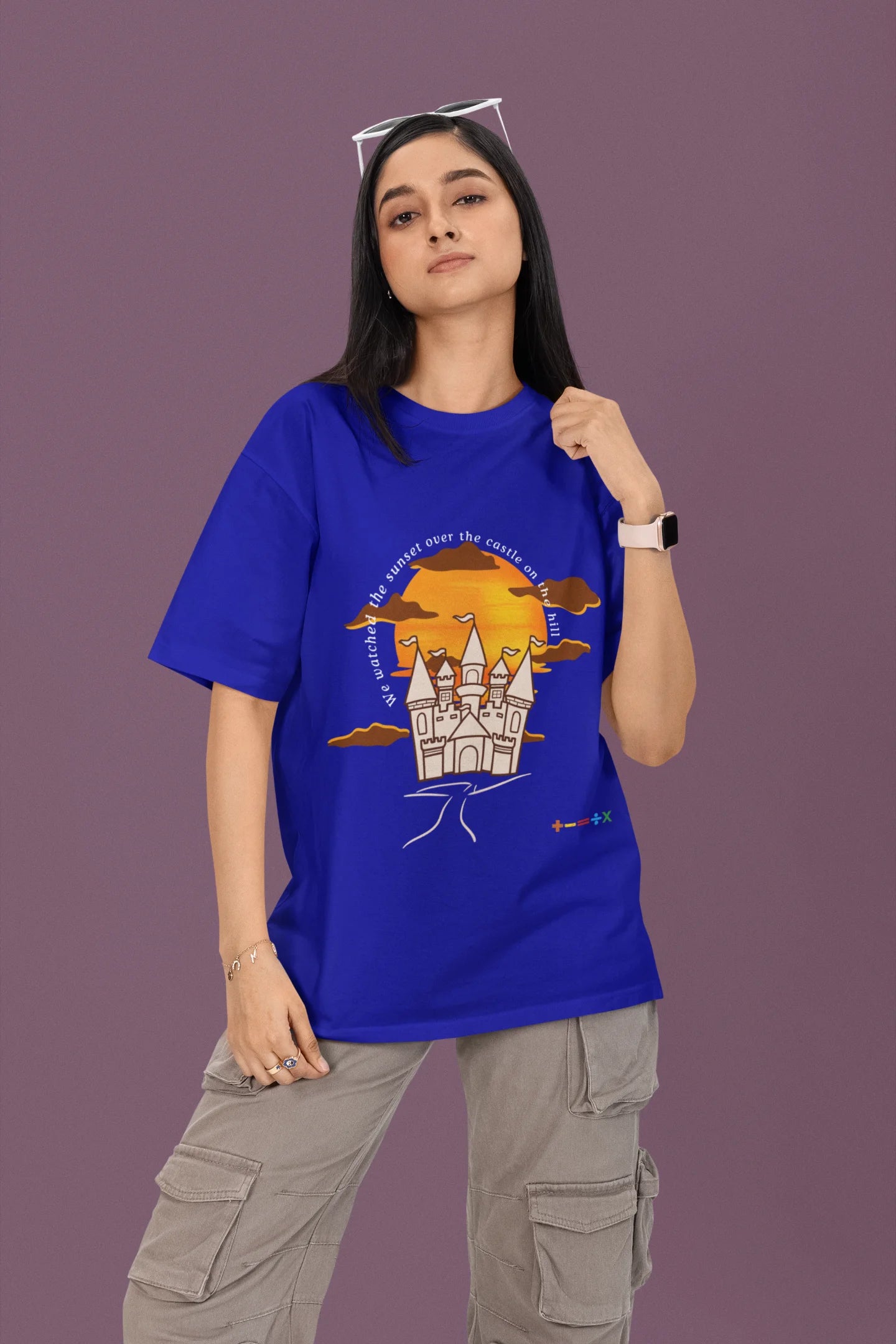 First front view of a female model wearing a royal blue oversized t-shirt featuring a nostalgic sunset and castle design, related to Ed Sheeran's "Castle on the Hill."