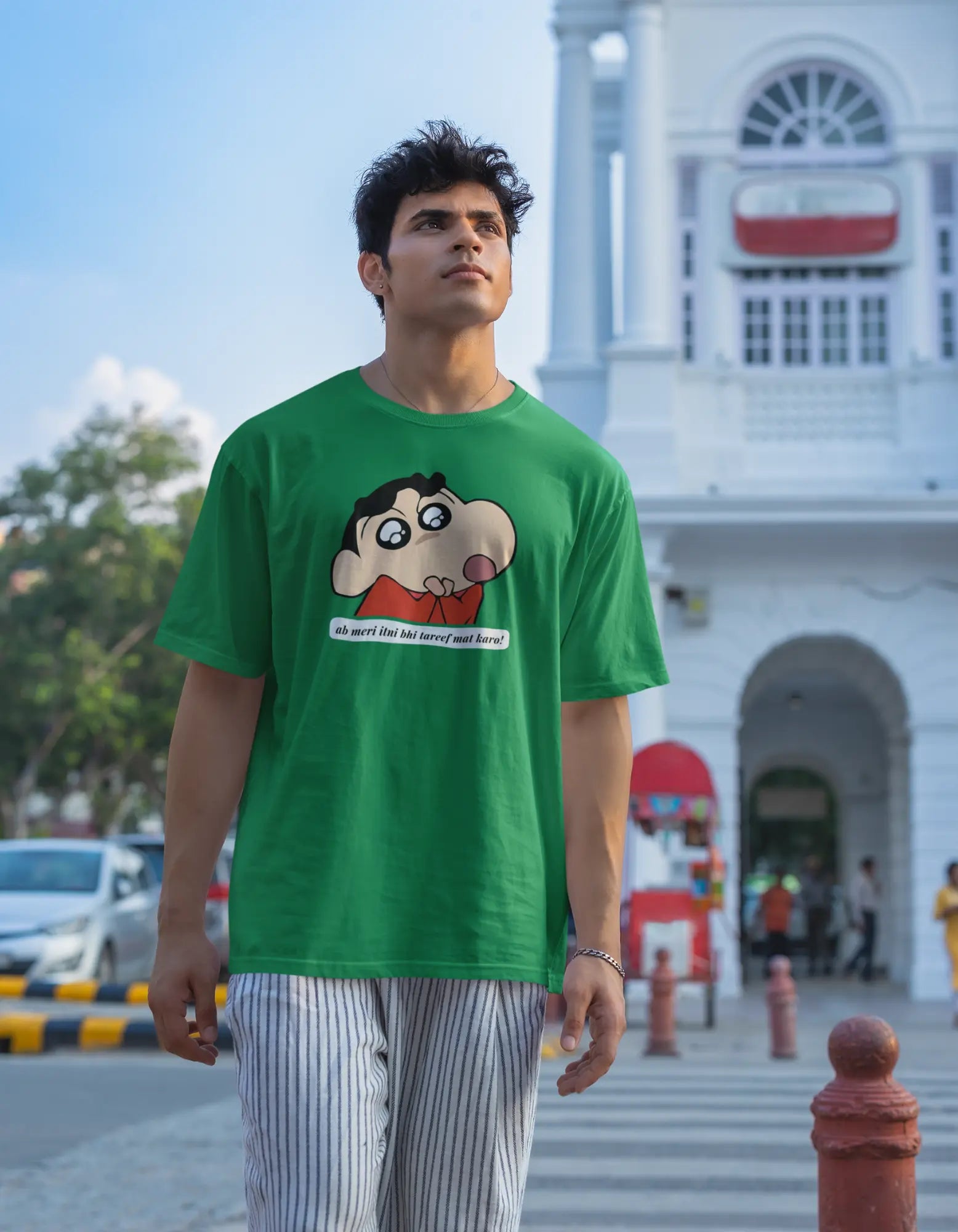 Second front view of male model wearing an oversized forest green tee featuring Shinchan with the text "Don't Praise Me So Much" in Hindi. A perfect blend of humor and nostalgia for Shinchan fans.