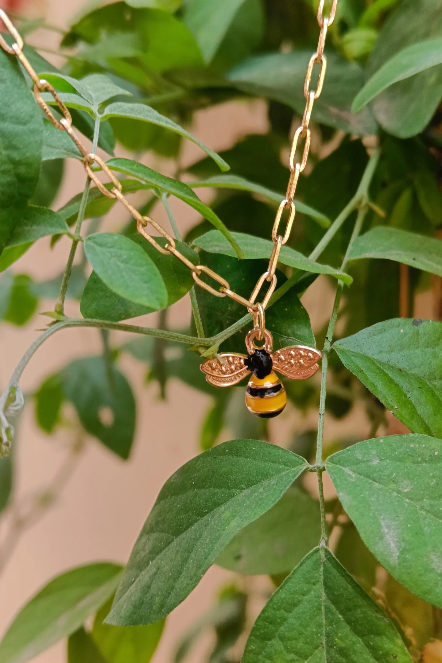 4th view of a gold chain necklace with a small pendant shaped like a honey bee.