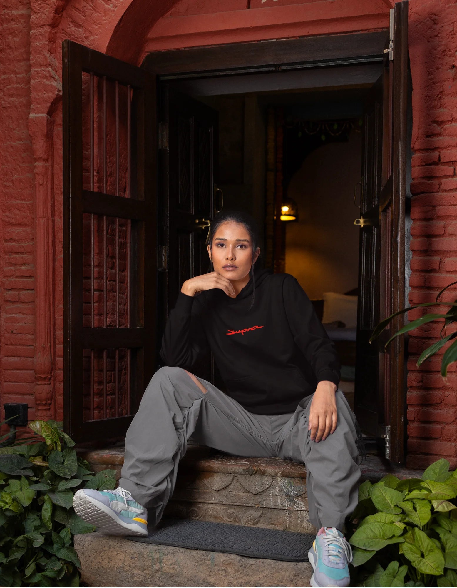 Third front view of a female model wearing a black hoodie featuring a Toyota Supra design, exuding speed and power.