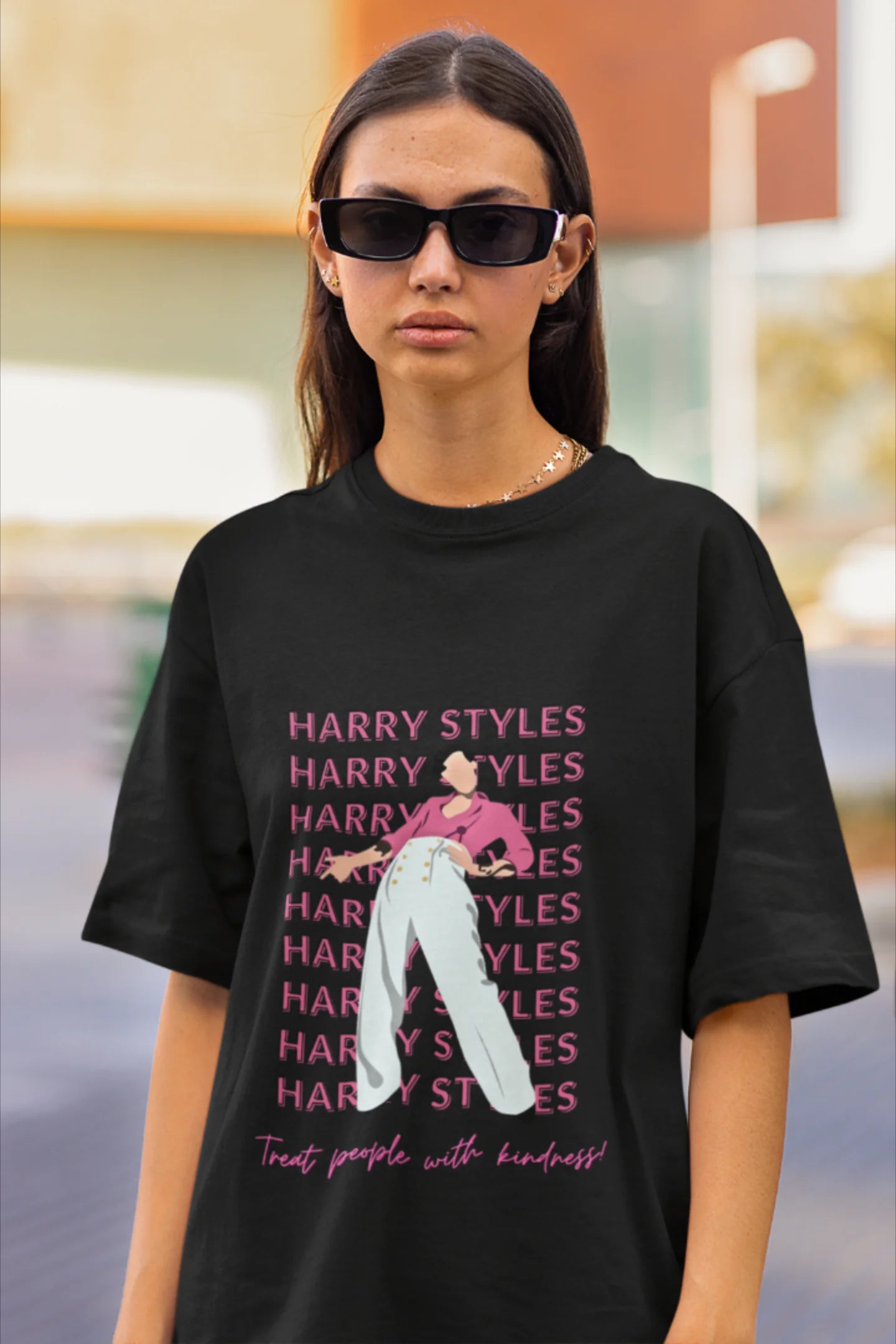 First image of female model wearing black oversized t-shirt inspired by Harry Styles, featuring the 'Treat People with Kindness' mantra from the Fine Line collection.