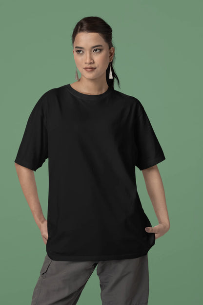 Front view of a female model wearing a black oversized tee with a heron taking off under the moonlight.