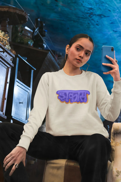 5th front view of a female model wearing an cream sweatshirt featuring "Jhakas" in a stylish font.