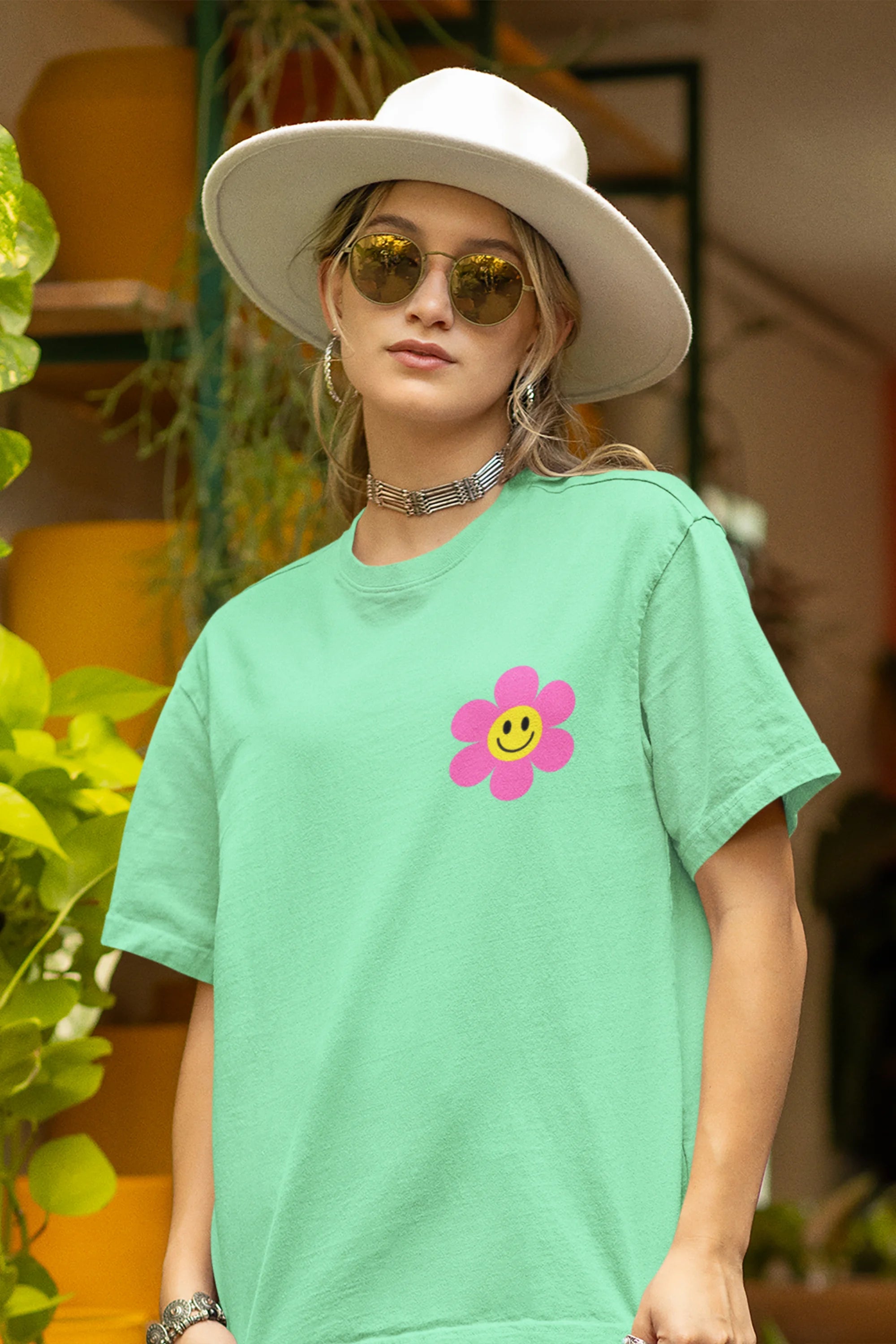 Close up view of a female model wearing an oversized mint green t-shirt with a positive message "Keep Smiling" surrounded by colorful flowers and a smiley face emoji. Ideal for those who love cheerful clothing and spreading positivity.