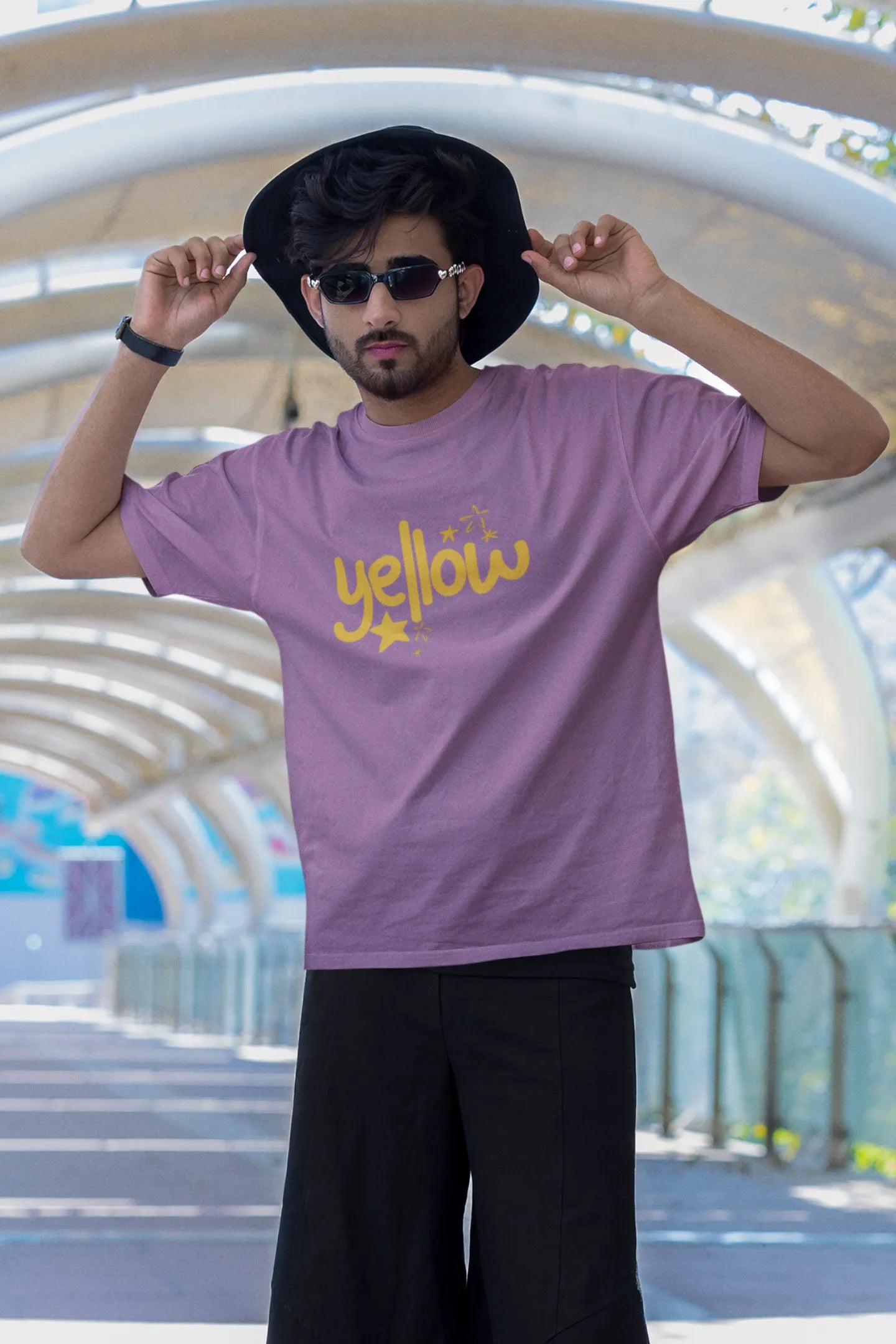 Third front view of a male model wearing a dirty purple oversized t-shirt with the "Yellow" album artwork by Coldplay.