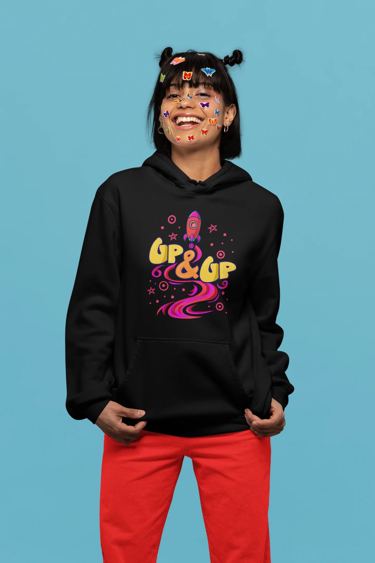 Fifth front view of a female model wearing an black hoodie with a rocket ship design and the text "Up & Up".