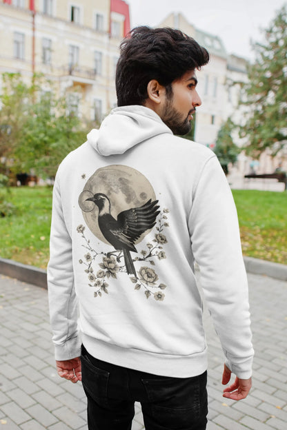 Back view of a male model wearing a white hoodie with a heron taking off under the moonlight.