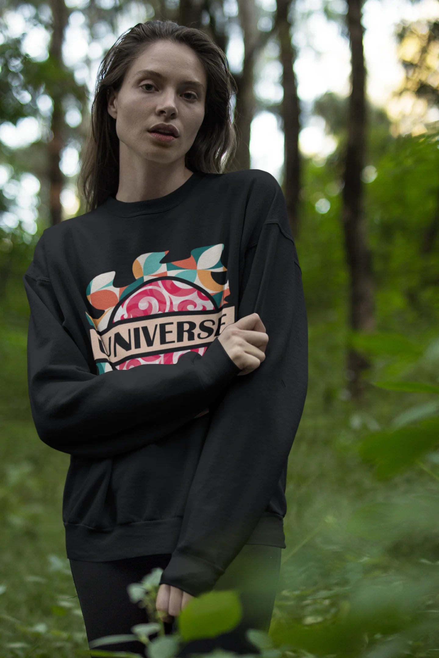Fourth front view of a female model wearing an black sweatshirt with a cosmic Universe design inspired by Coldplay.