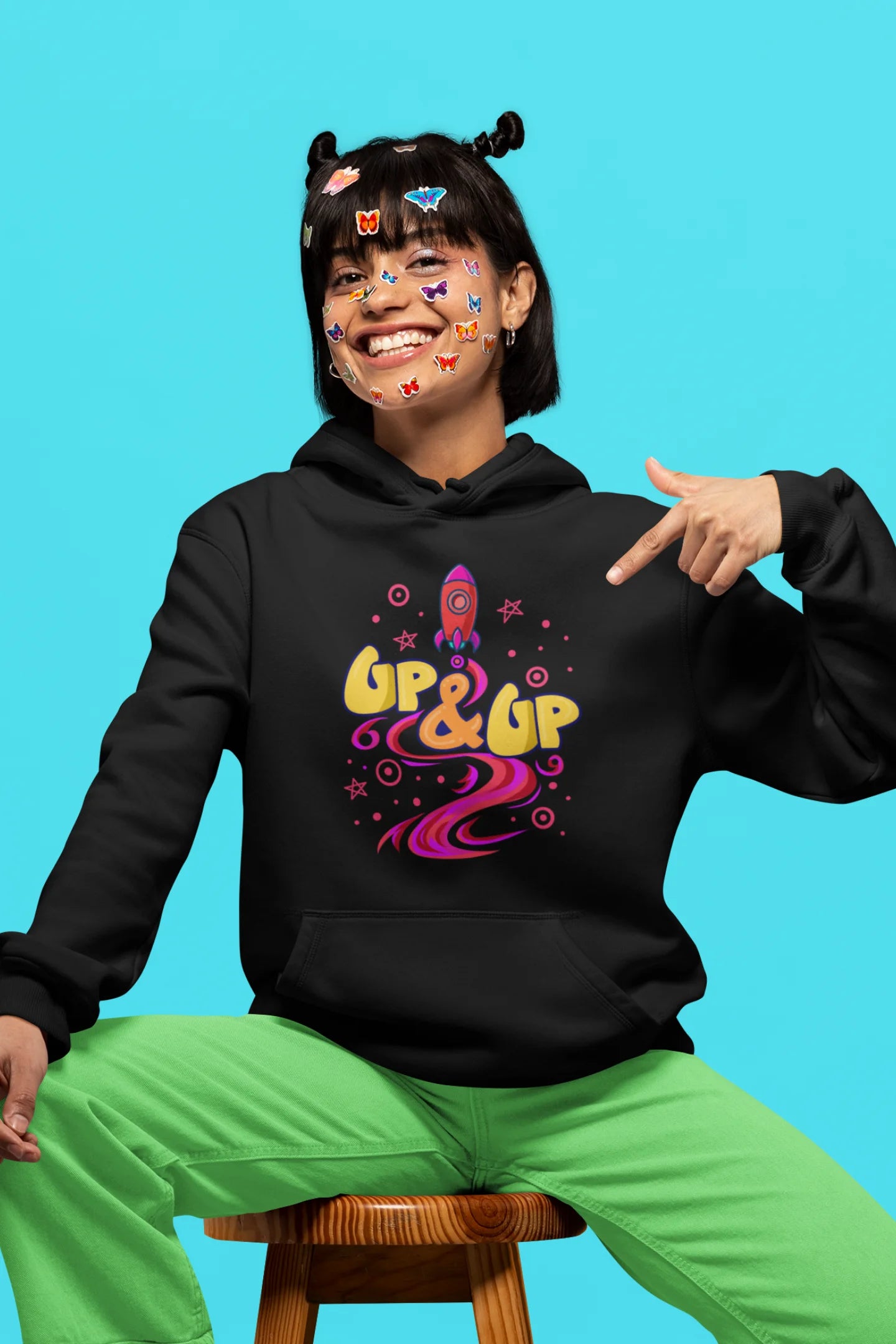 Third front view of a female model wearing an black hoodie with a rocket ship design and the text "Up & Up".
