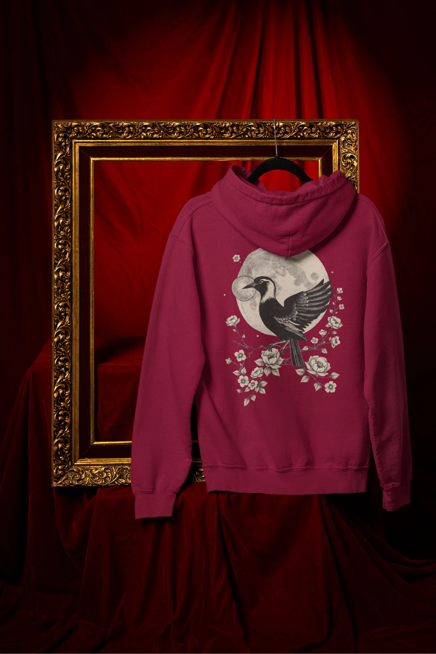 Back view of a maroon hoodie with a heron taking off under the moonlight.