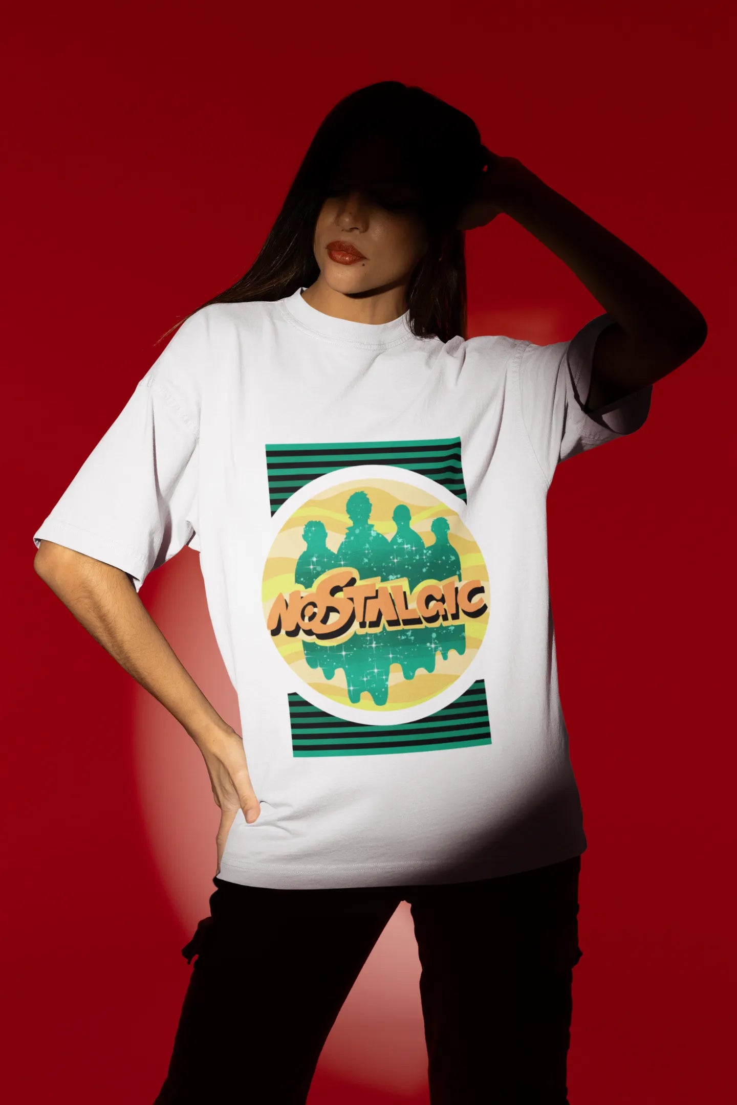 First view of a female model wearing an oversized off-white t-shirt with a shadow silhouette of the Coldplay band members and the word "Nostalgic" printed on it.