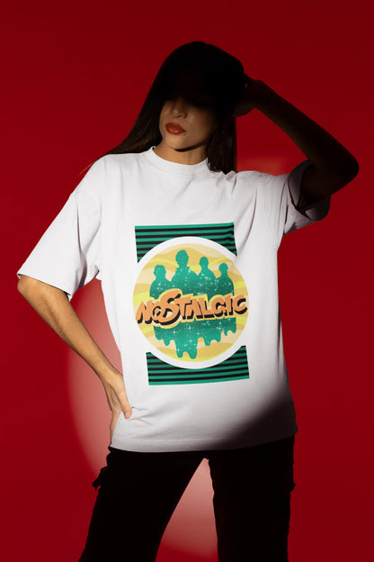 First view of a female model wearing an oversized off-white t-shirt with a shadow silhouette of the Coldplay band members and the word "Nostalgic" printed on it.