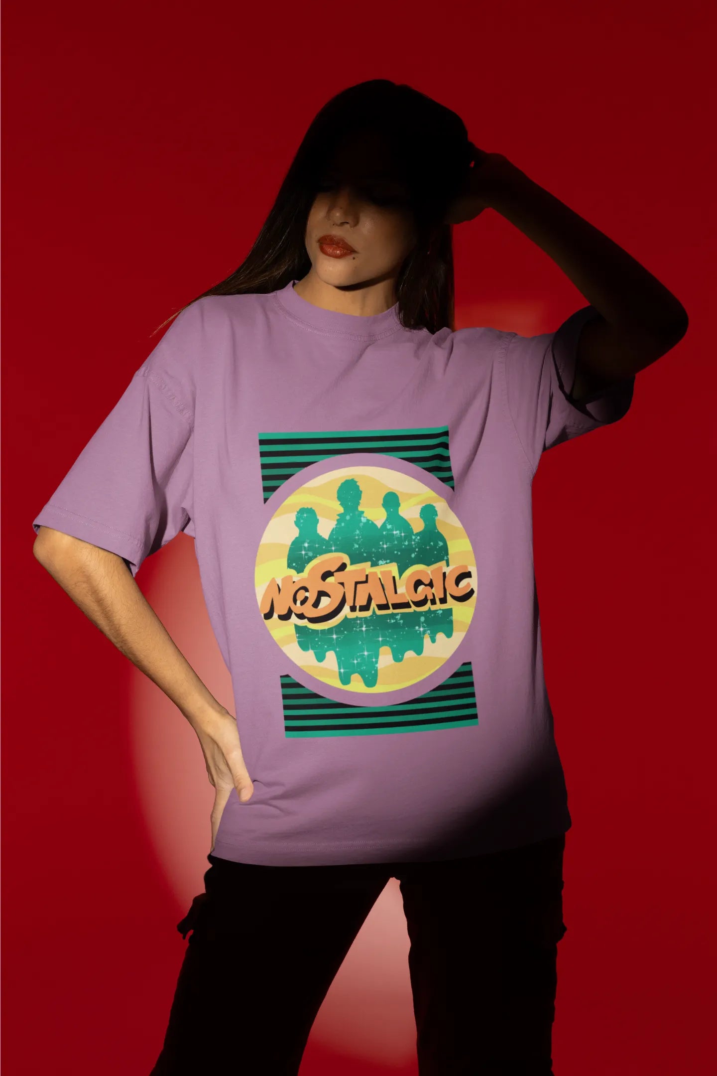 First view of a female model wearing an oversized dirty purple t-shirt with a shadow silhouette of the Coldplay band members and the word "Nostalgic" printed on it.