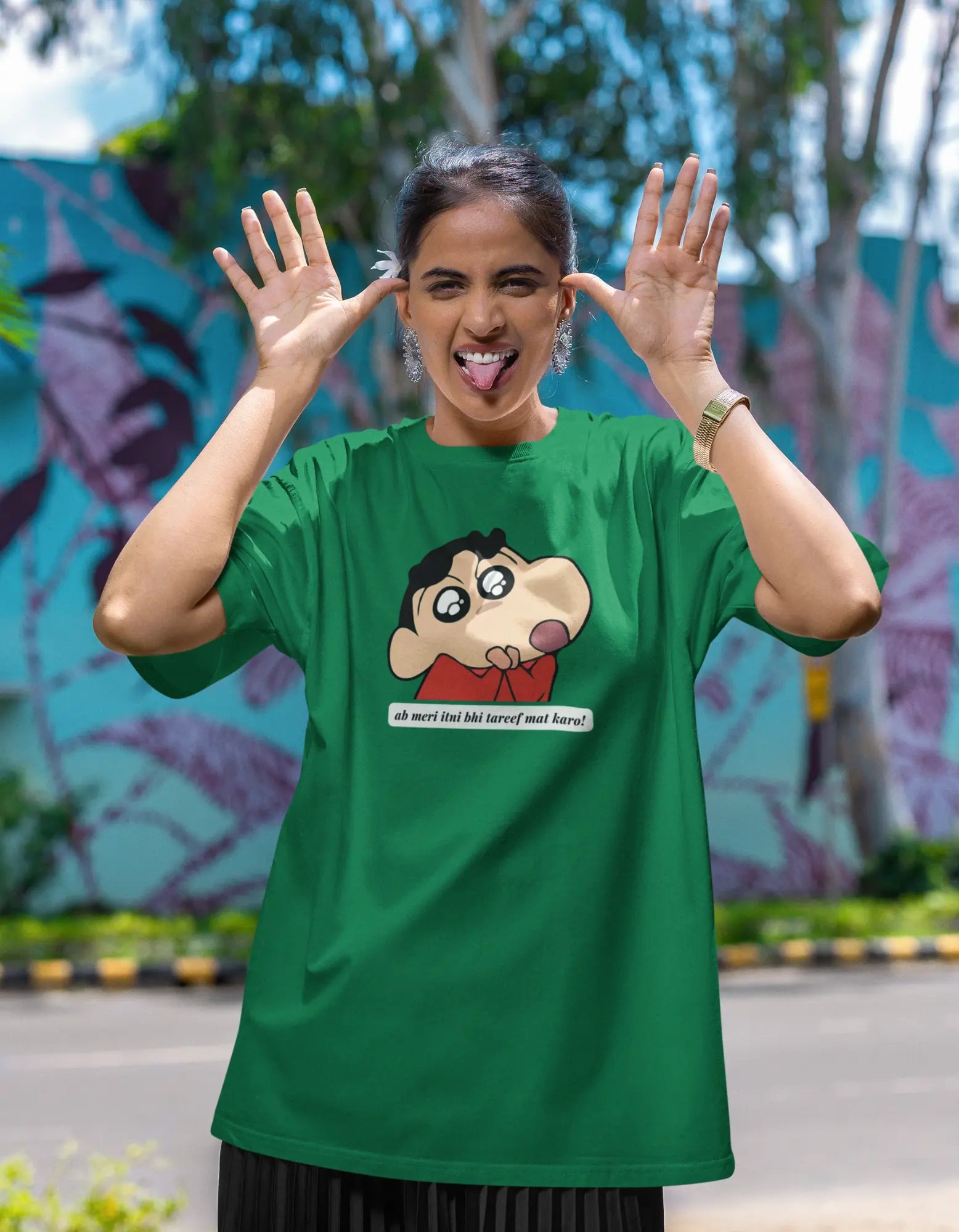 First front view of female model wearing an oversized forest green tee featuring Shinchan with the text "Don't Praise Me So Much" in Hindi. A perfect blend of humor and nostalgia for Shinchan fans.