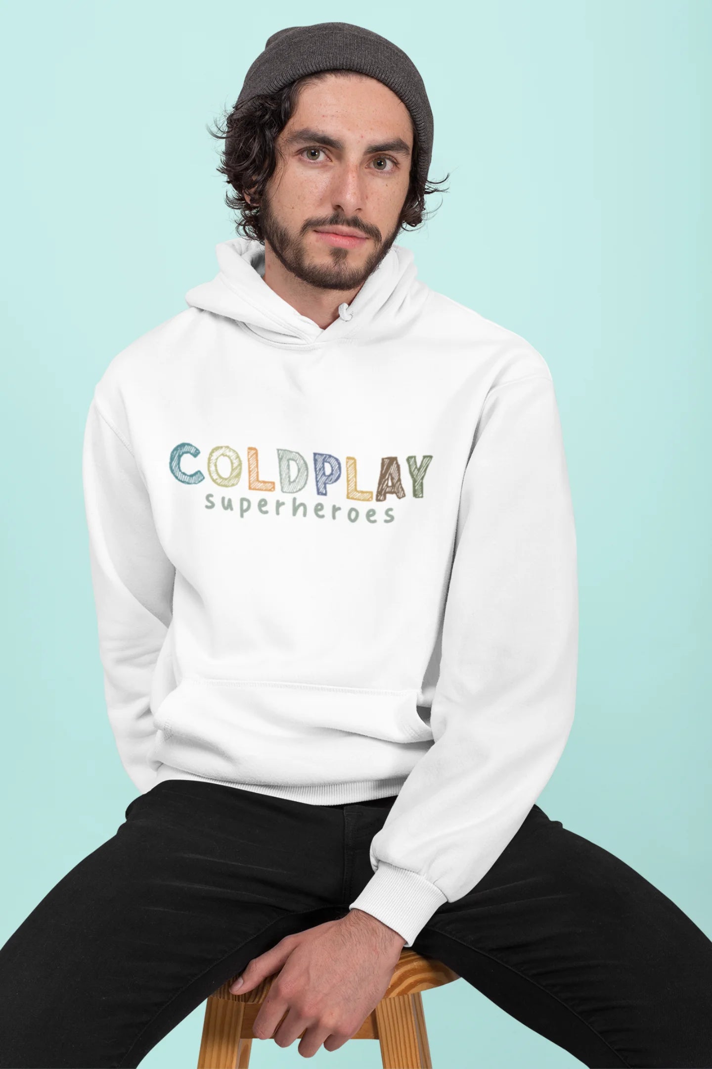 2nd front view of a male model wearing an off-white hoodie with a design inspired by the "Something Just Like This" music video, featuring the word "Superheroes".