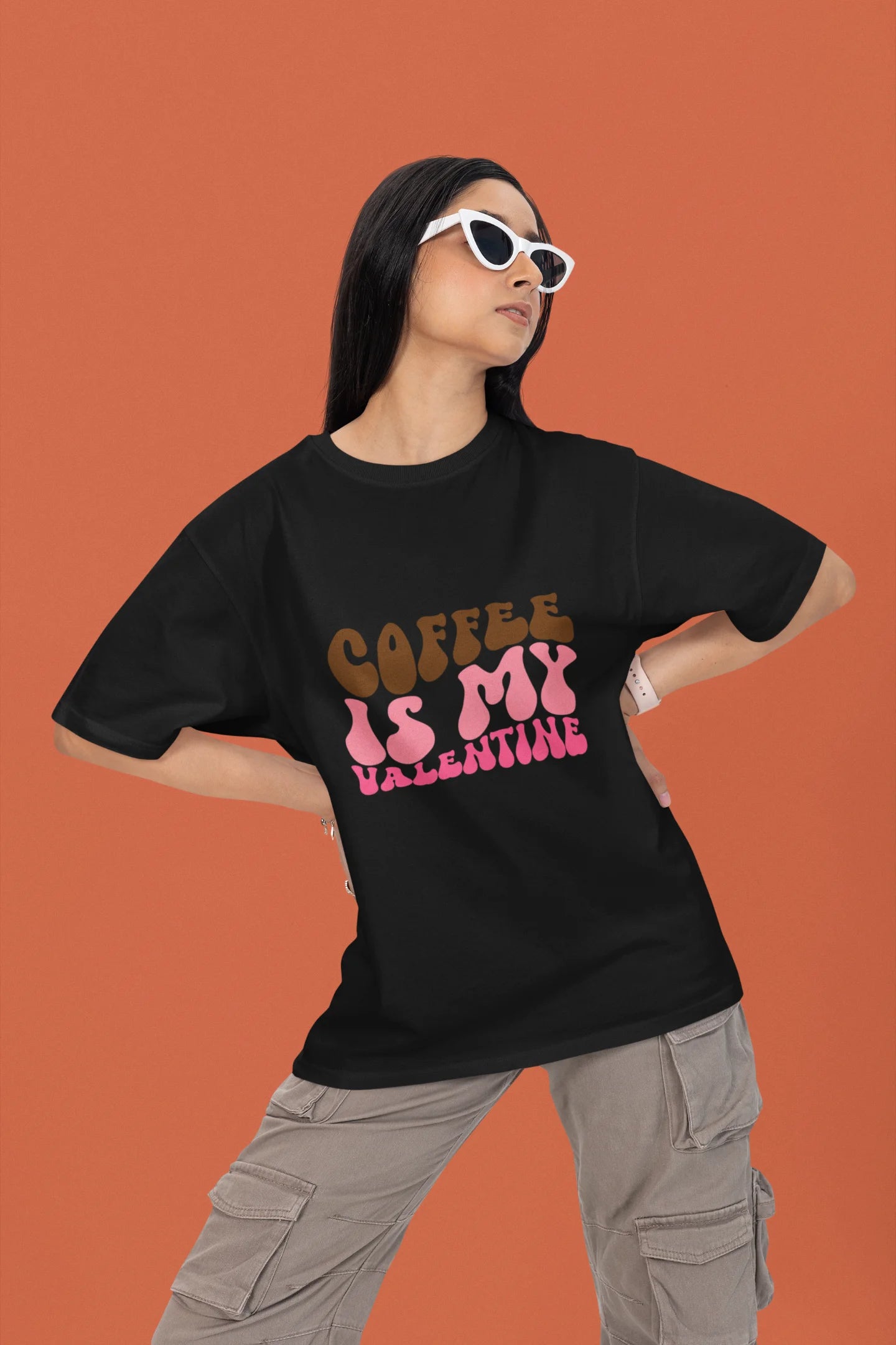 First front view of a female model wearing a black oversized t-shirt with the text "Coffee is My Valentine" printed on it.