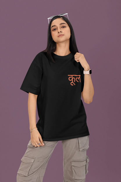 First front view of a female model wearing a black oversized t-shirt featuring the Hindi word for "cool" with a unique, playful design.