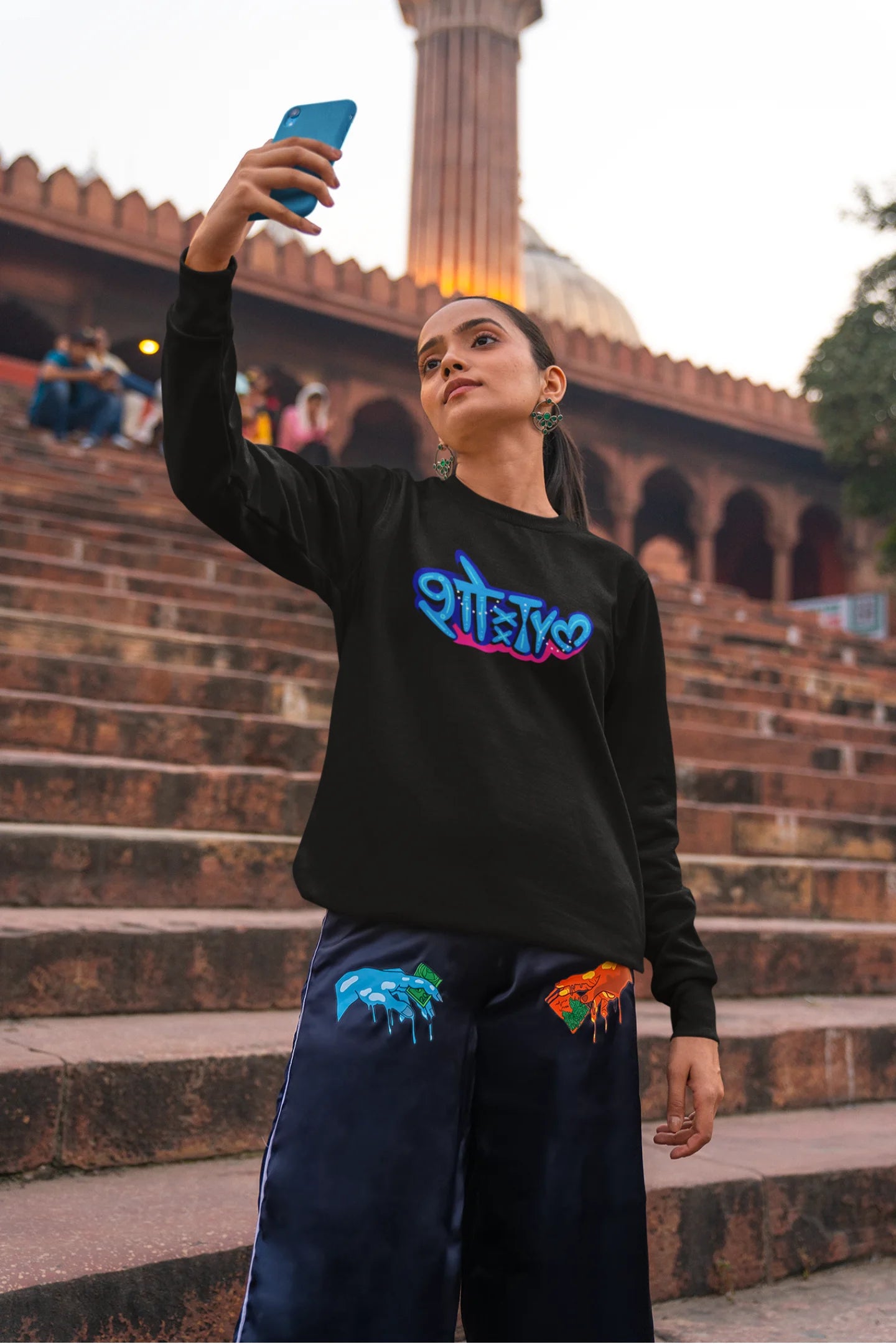 3rd front view of a female model wearing a black oversized t-shirt featuring "Showtime" in Hindi.