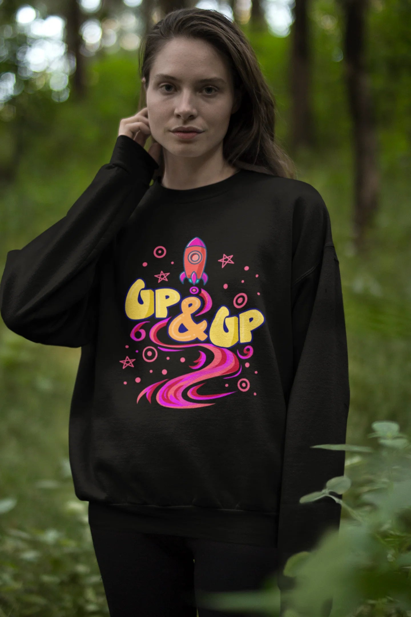 Third front view of a female model wearing an black sweatshirt with a rocket ship design and the text "Up & Up".