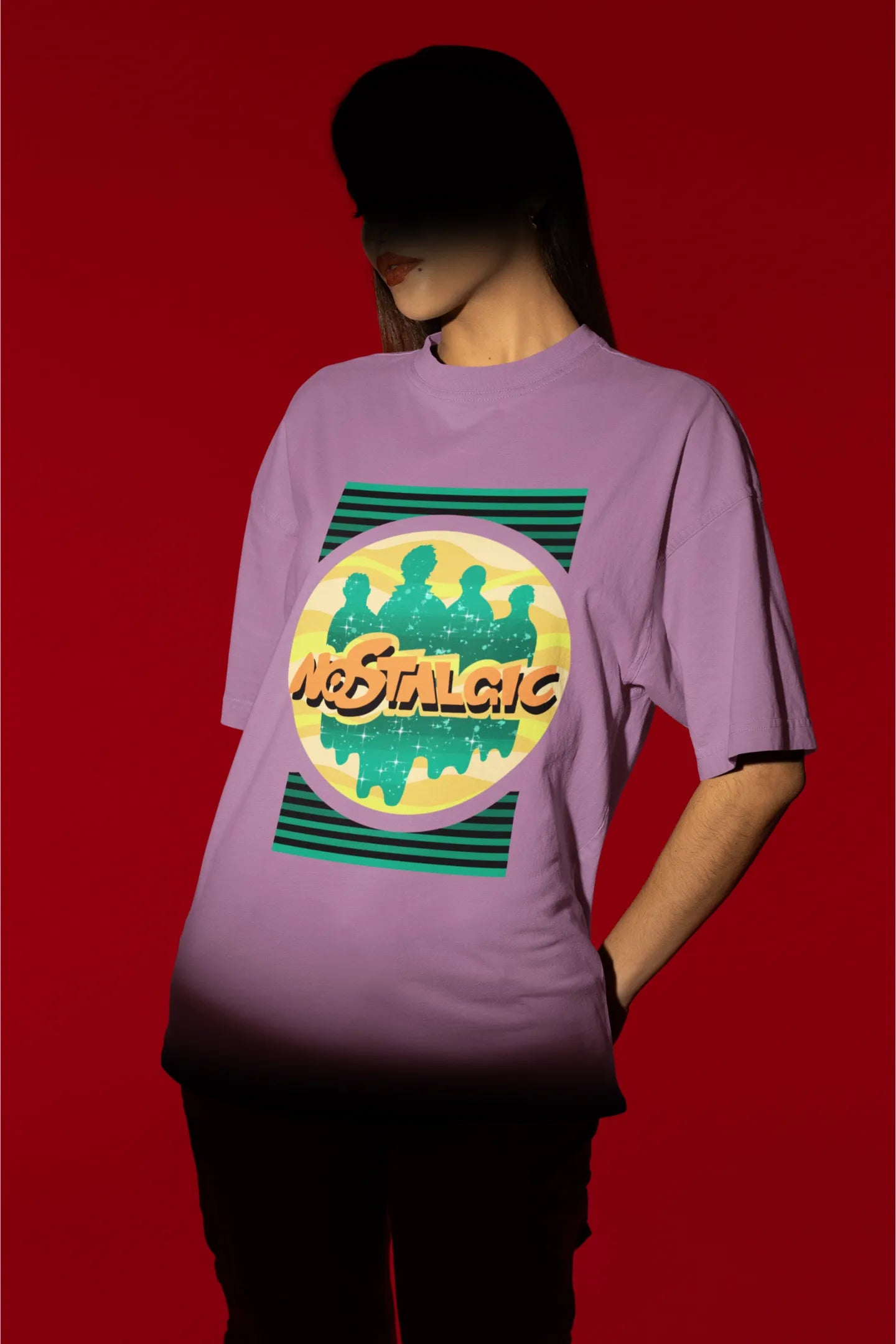 Third view of a female model wearing an oversized dirty purple t-shirt with a shadow silhouette of the Coldplay band members and the word "Nostalgic" printed on it.