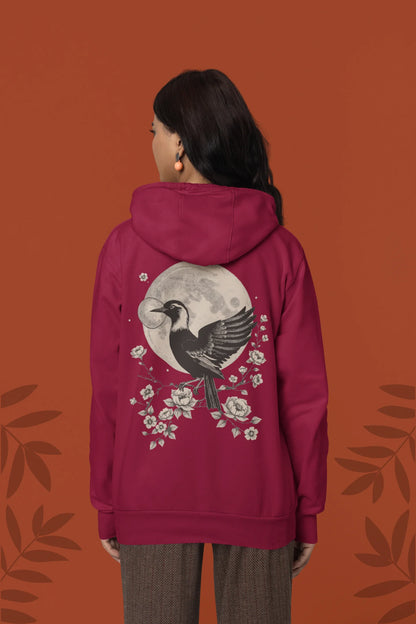 Back view of a female model wearing a maroon hoodie with a heron taking off under the moonlight.