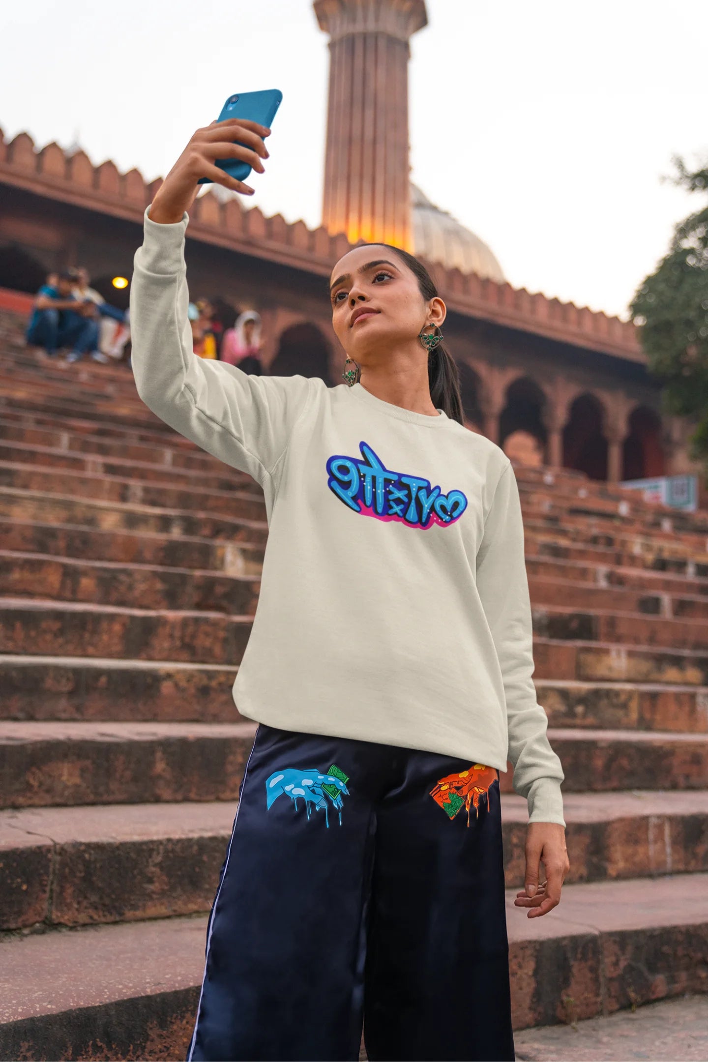 4th front view of a female model wearing a cream oversized t-shirt featuring "Showtime" in Hindi.