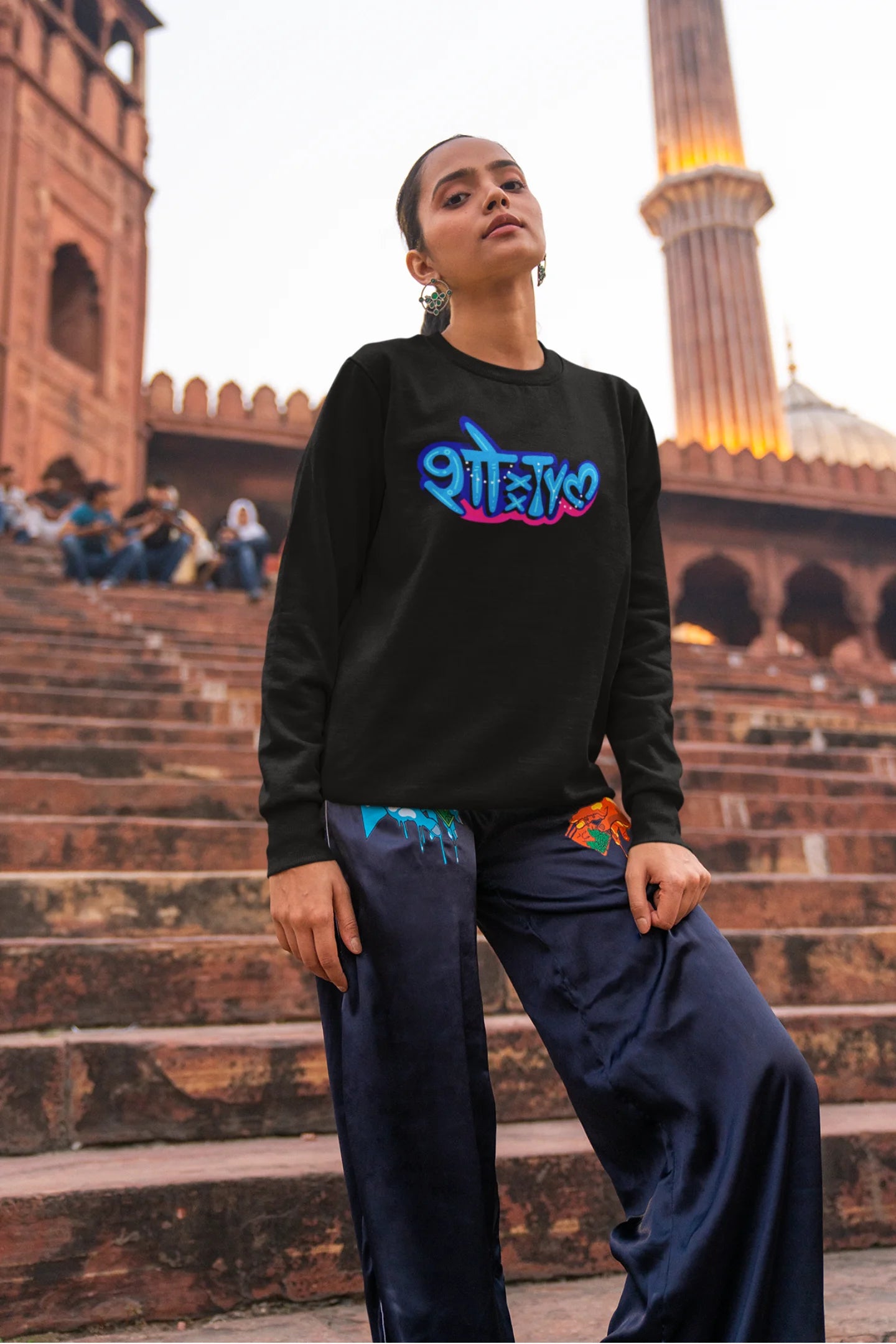 6th front view of a female model wearing a black oversized t-shirt featuring "Showtime" in Hindi.