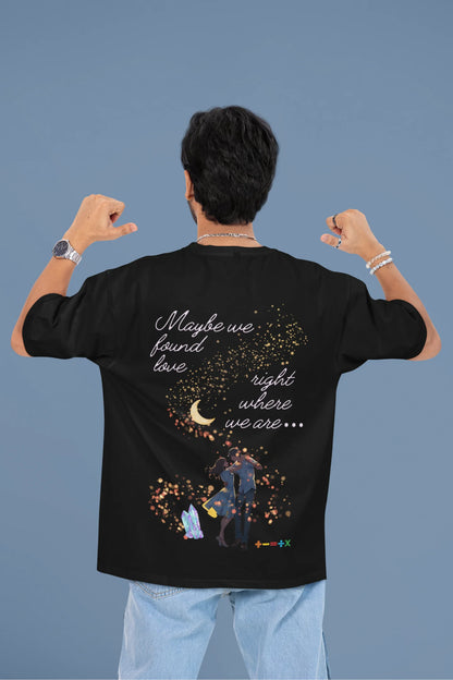 Back view of a male model wearing a black oversized t-shirt featuring a couple dancing in the moonlight, inspired by Ed Sheeran's themes of love.