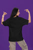 Back view of a female model wearing a black oversized t-shirt with the text 