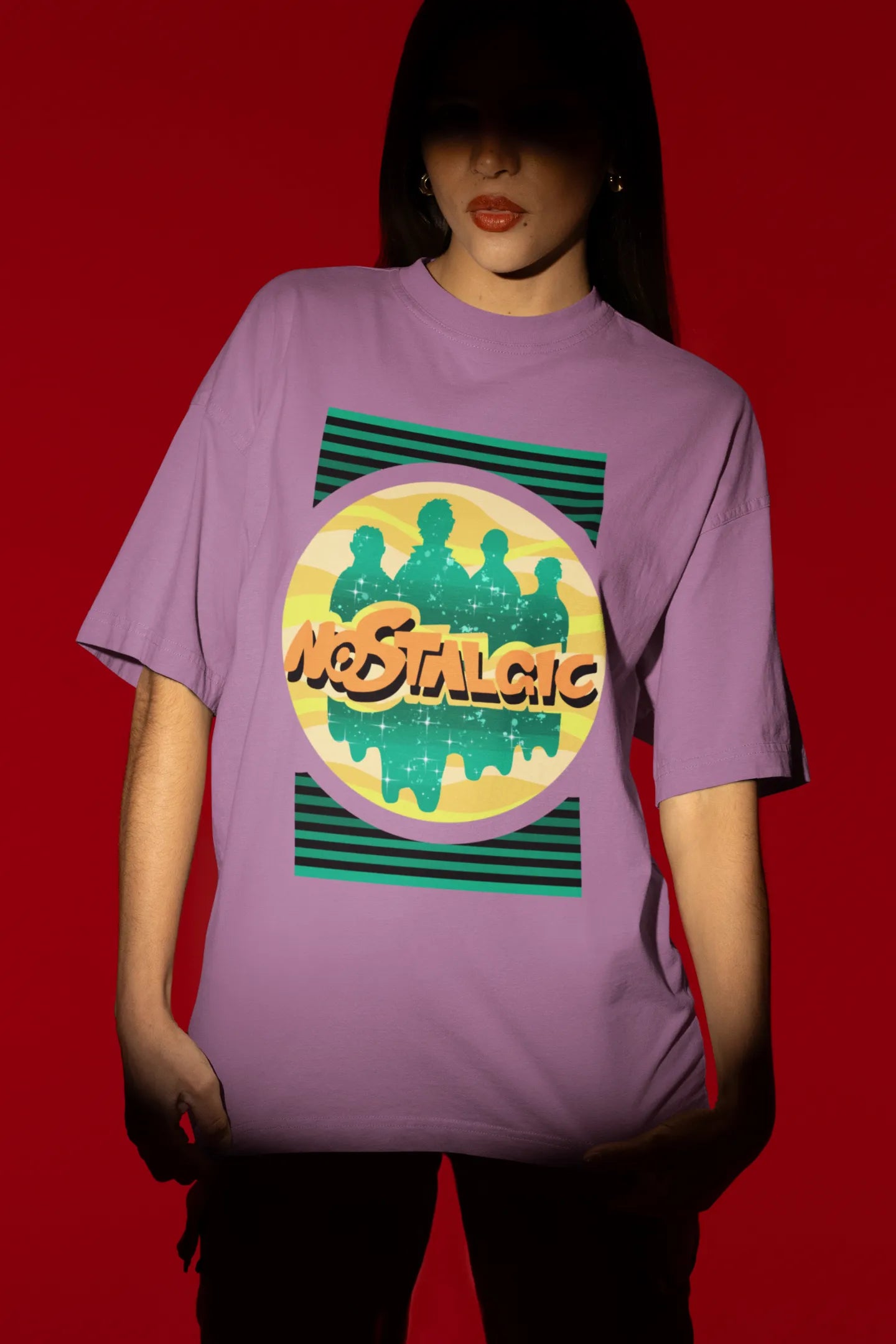 Fourth view of a female model wearing an oversized dirty purple t-shirt with a shadow silhouette of the Coldplay band members and the word "Nostalgic" printed on it.