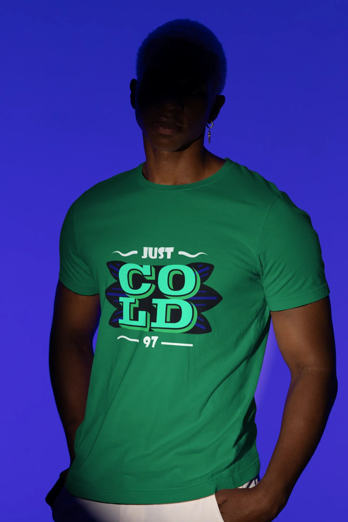 First front view of a male model wearing an forest green oversized t-shirt with the text "Just Cold" printed on it.